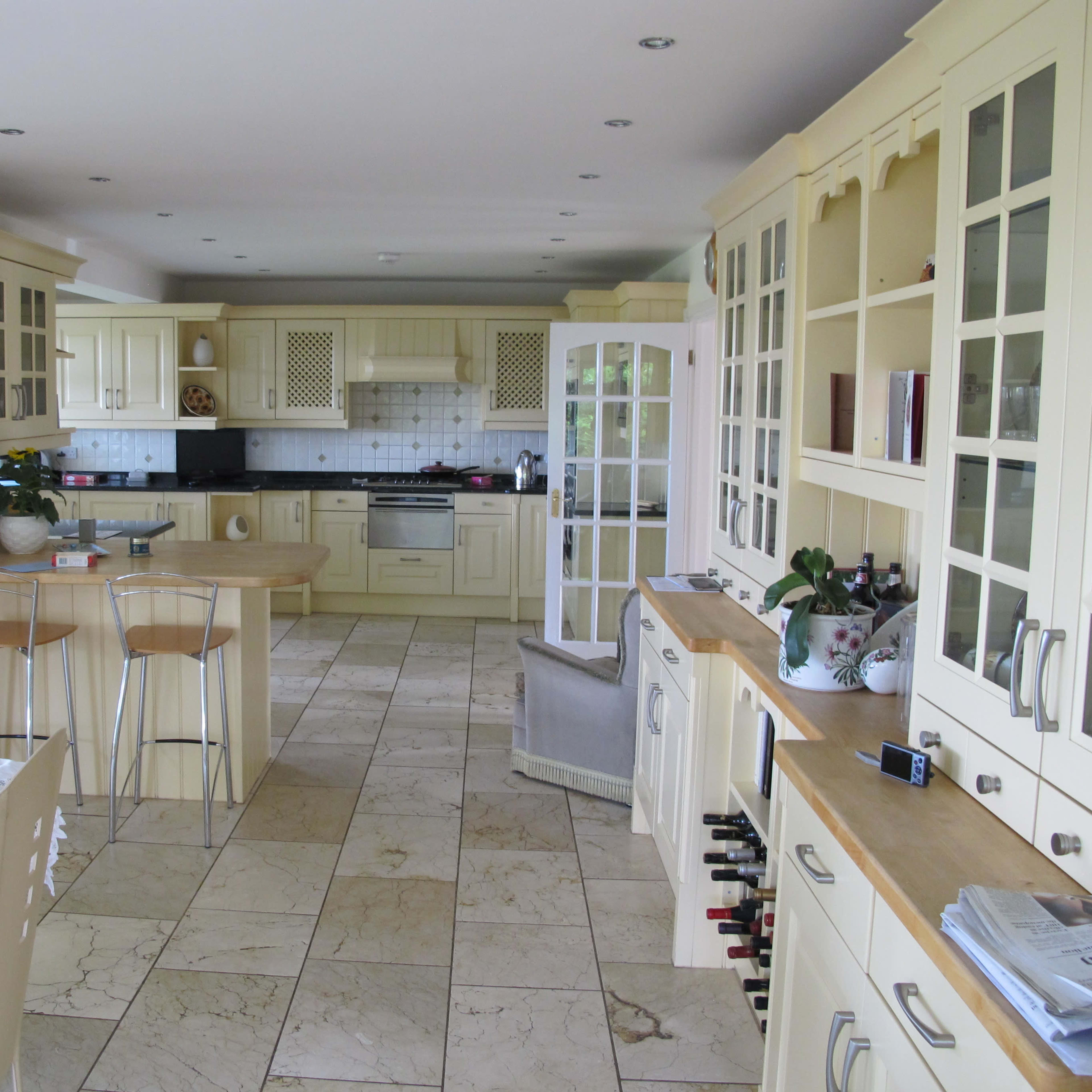 A spacious kitchen features cream-colored cabinetry, a central island with bar stools, and a tiled floor.