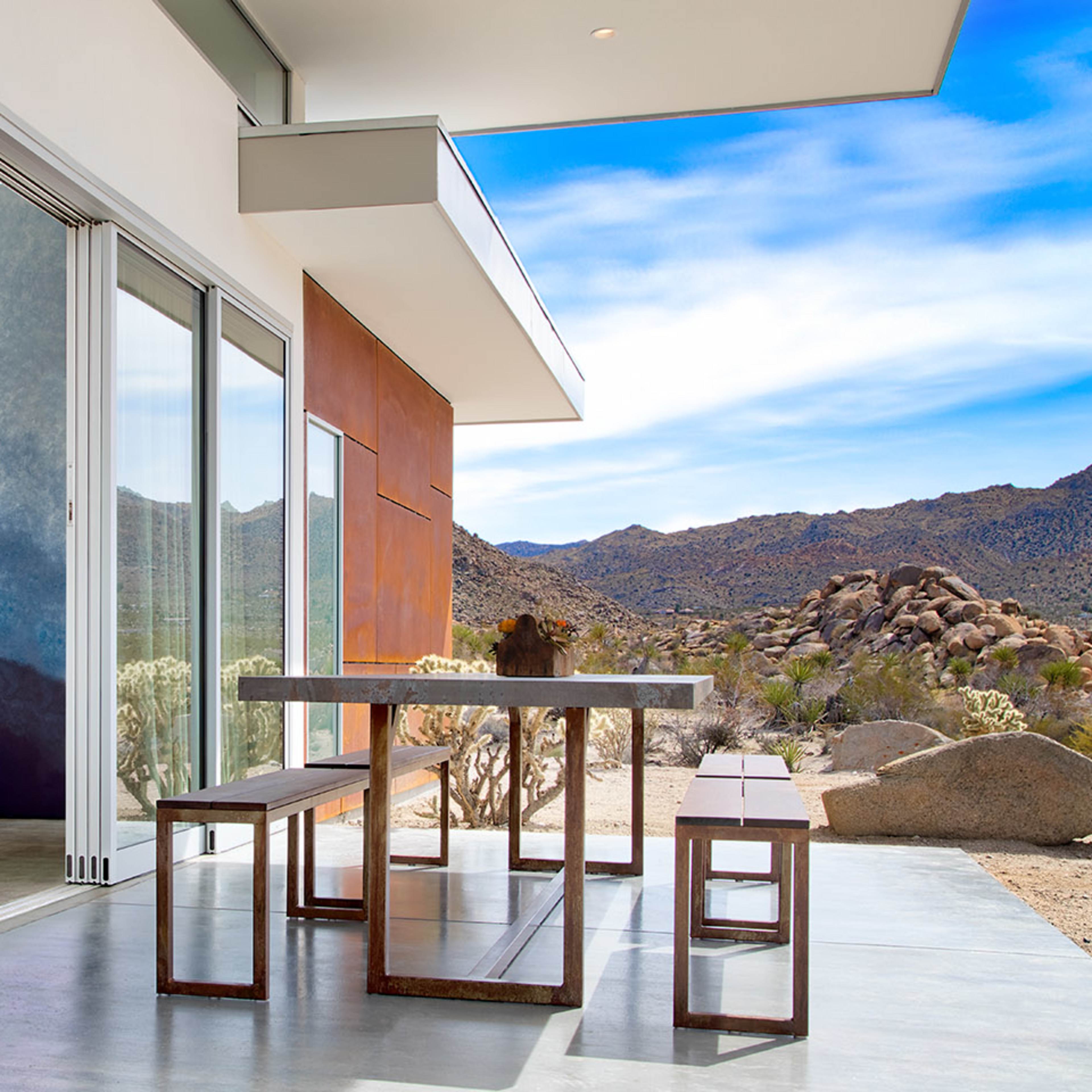 A modern interior space with large windows and a view of a rocky desert landscape.