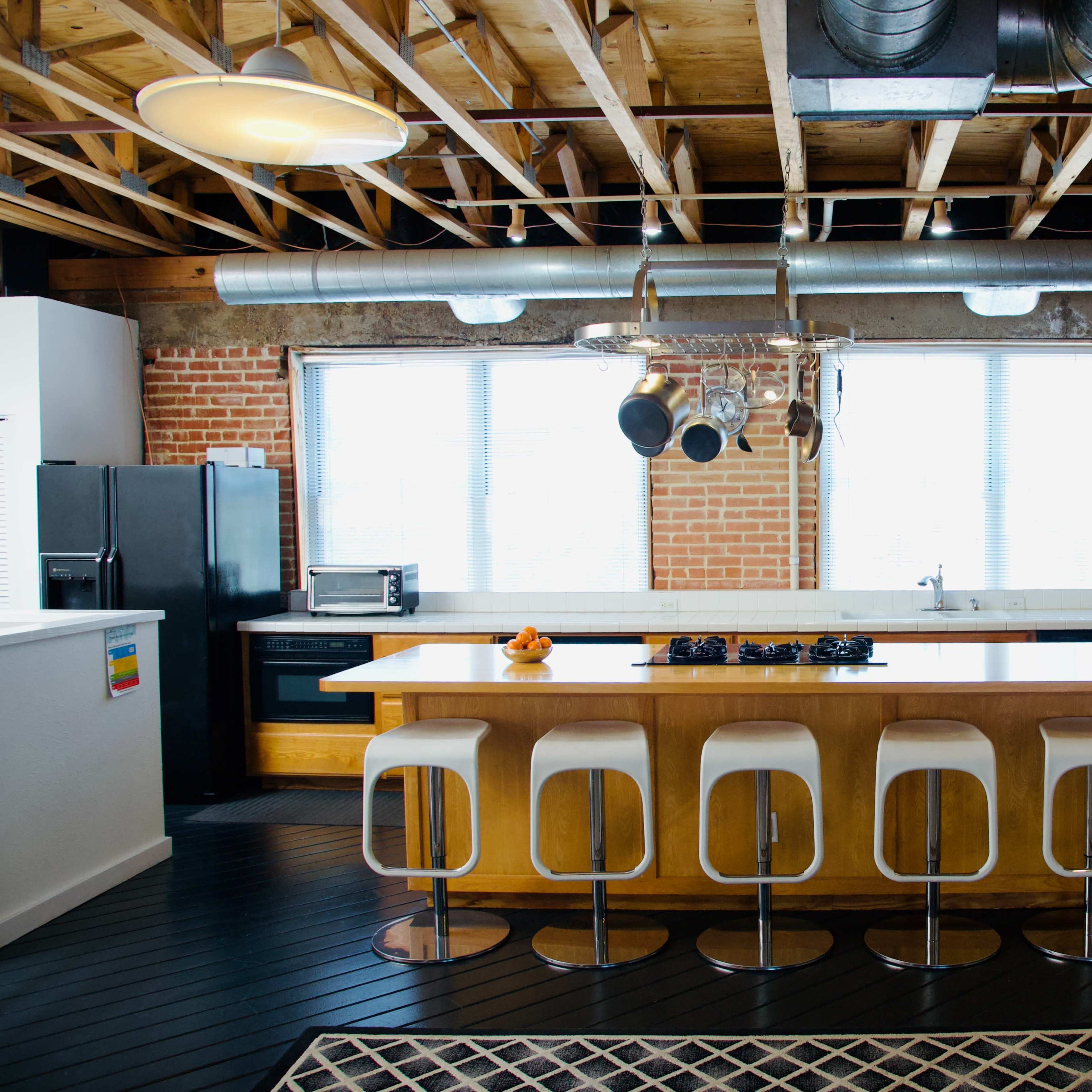 A modern kitchen with a large central island, wooden cabinetry, and exposed beams in the ceiling.