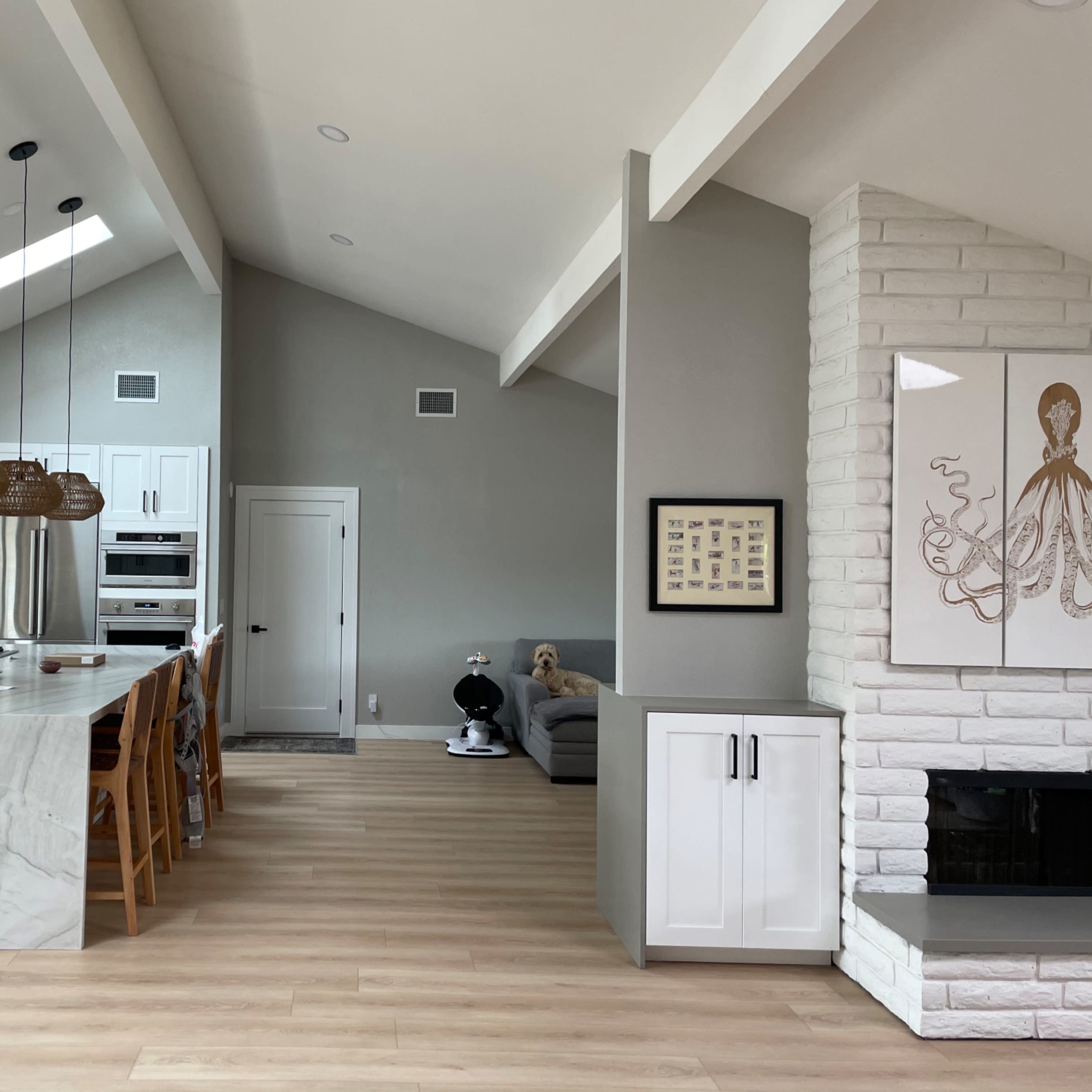 A modern kitchen and living area with a large island, white cabinetry, and a fireplace.