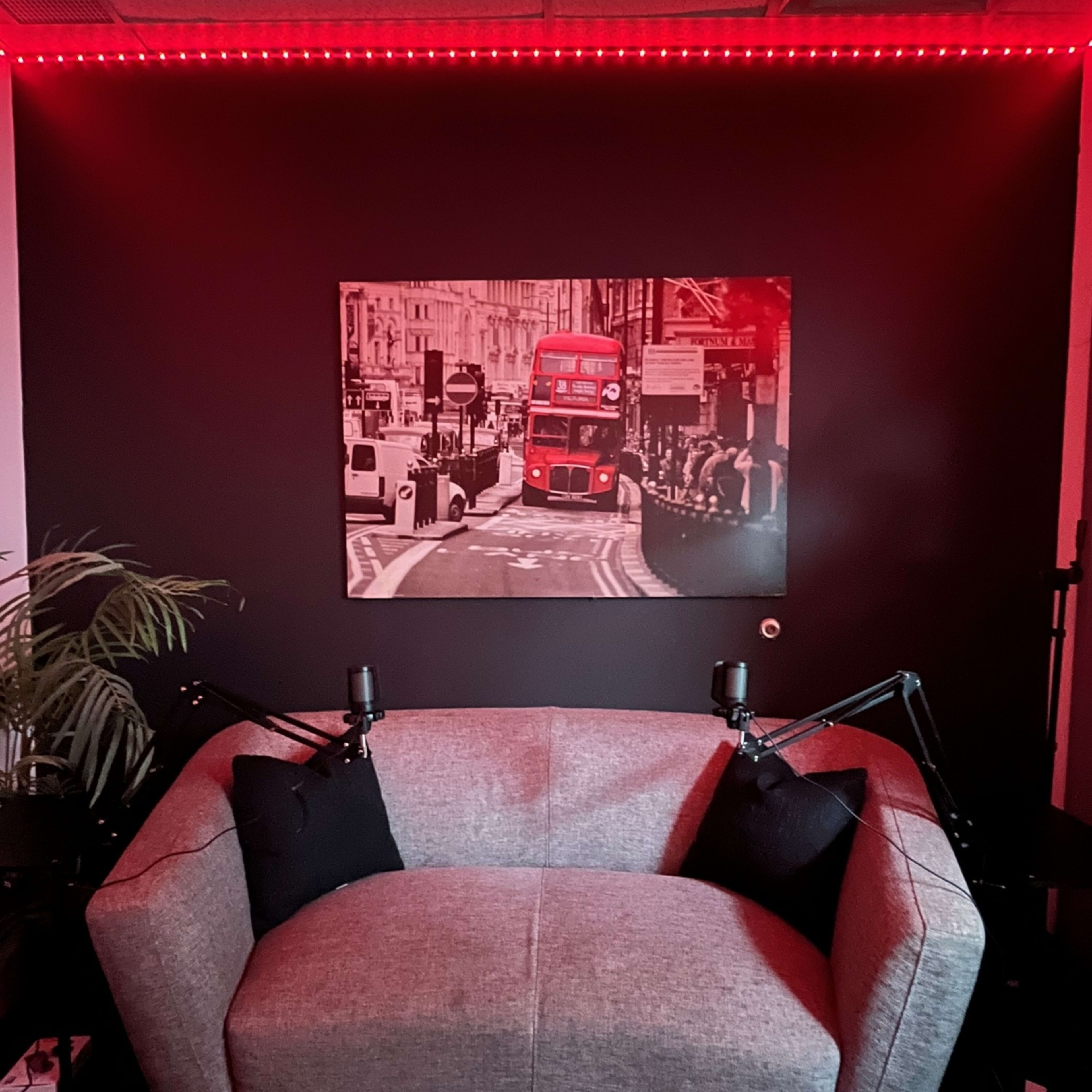 A gray sofa with black pillows is positioned in front of a black wall featuring a red-lit photograph of a London street scene.
