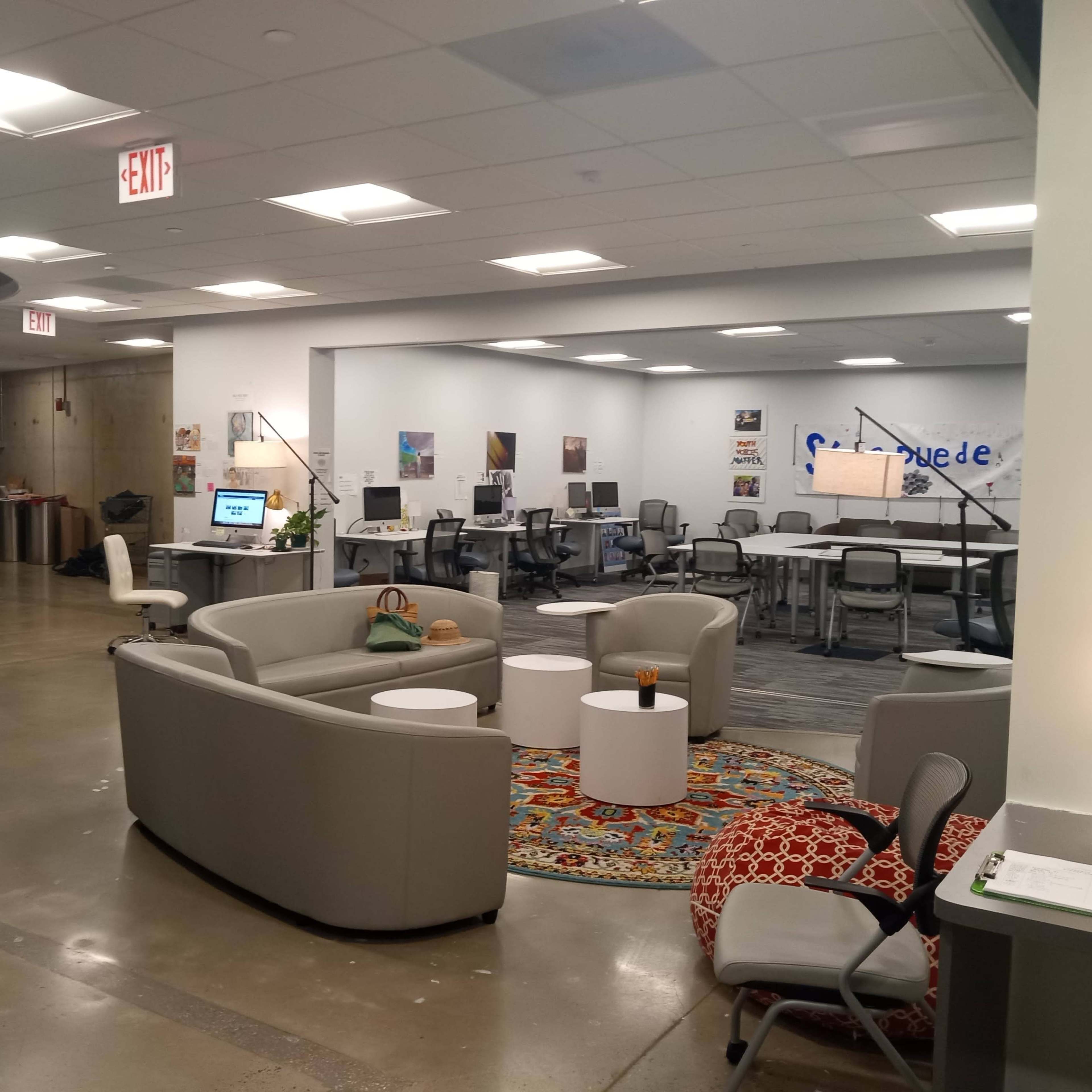 A modern, open office space with seating areas, workstations, and decorative artwork on the walls.