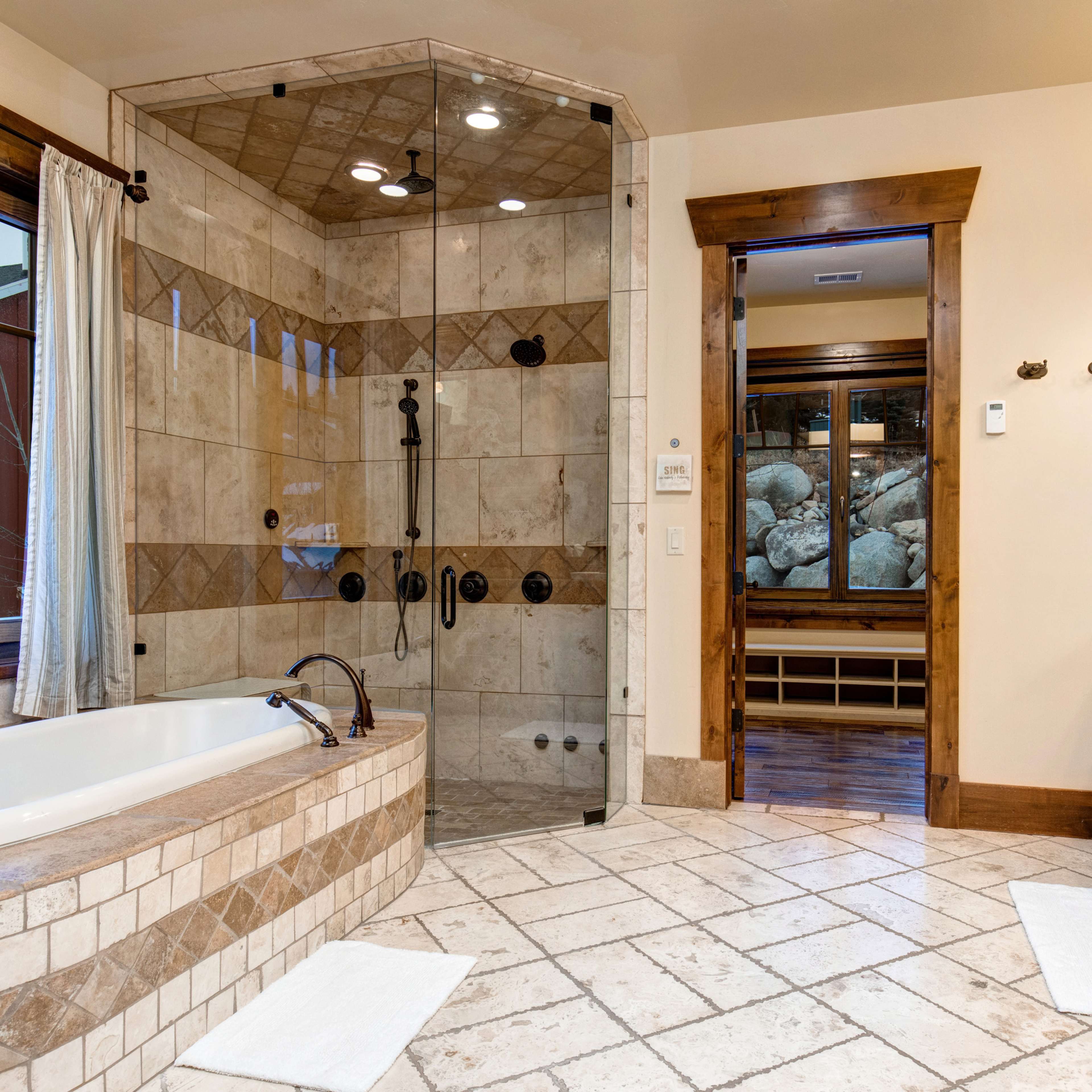 A spacious bathroom featuring a tiled shower area, a freestanding bathtub, and a wooden vanity with dual sinks.