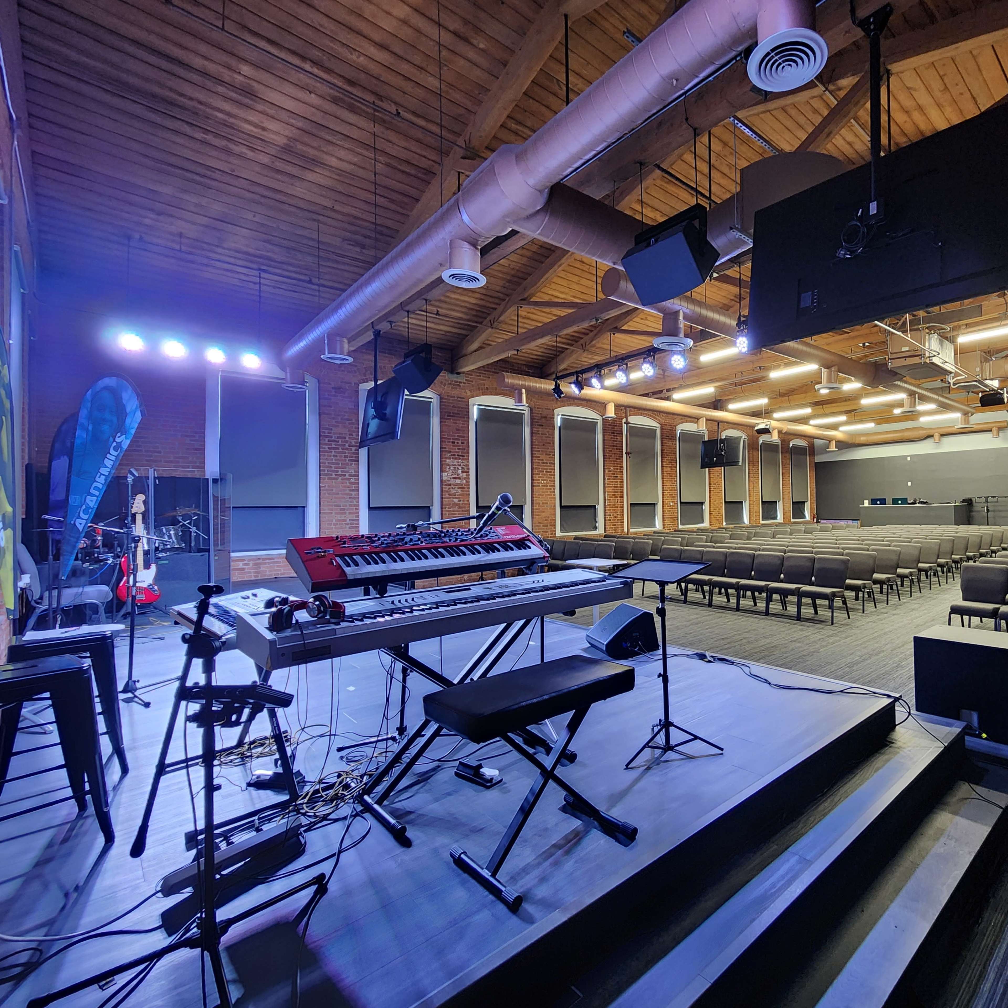 A stage setup with musical instruments in a spacious auditorium featuring rows of empty chairs.
