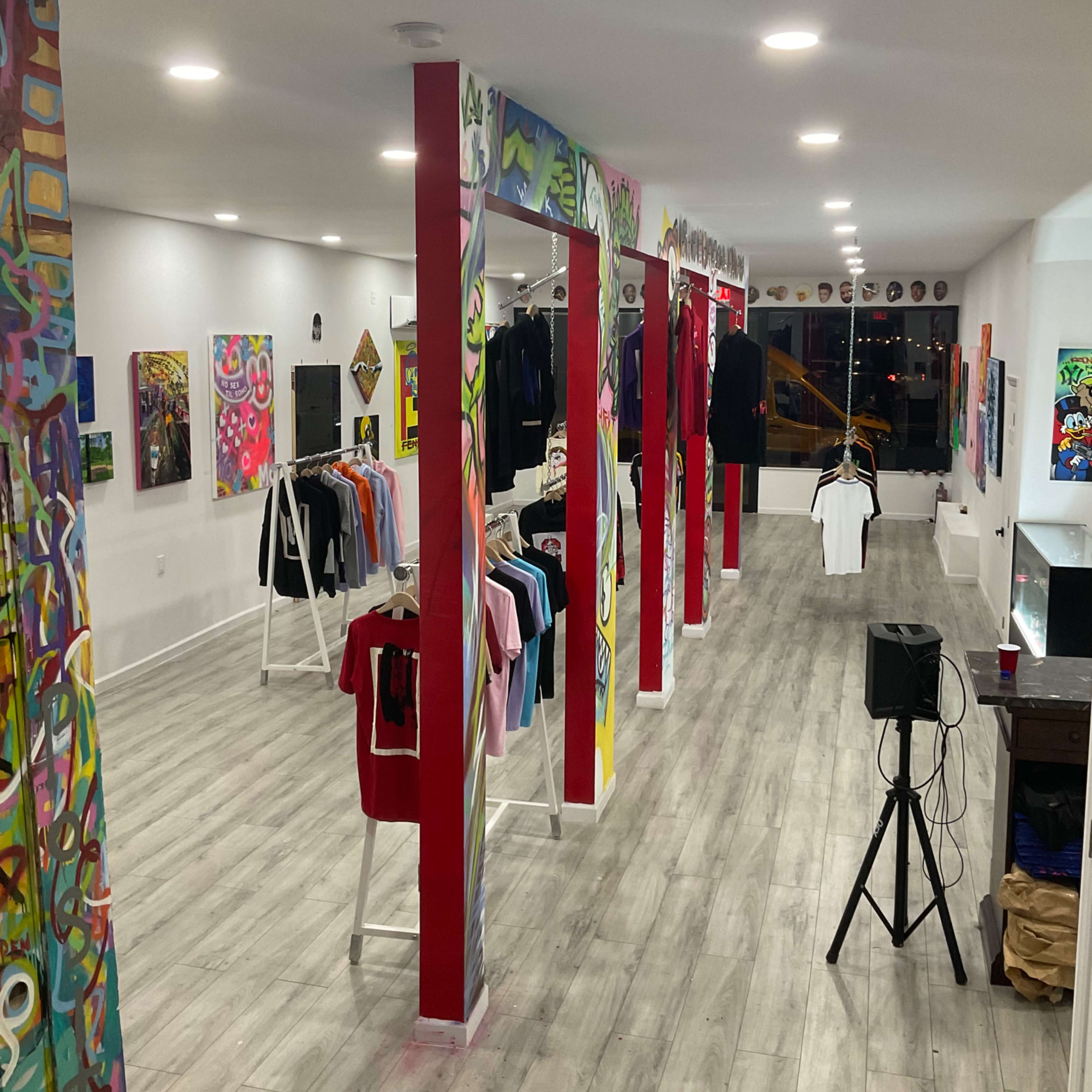 A clothing store featuring vibrant graffiti on the pillars and a display of various shirts arranged on racks.