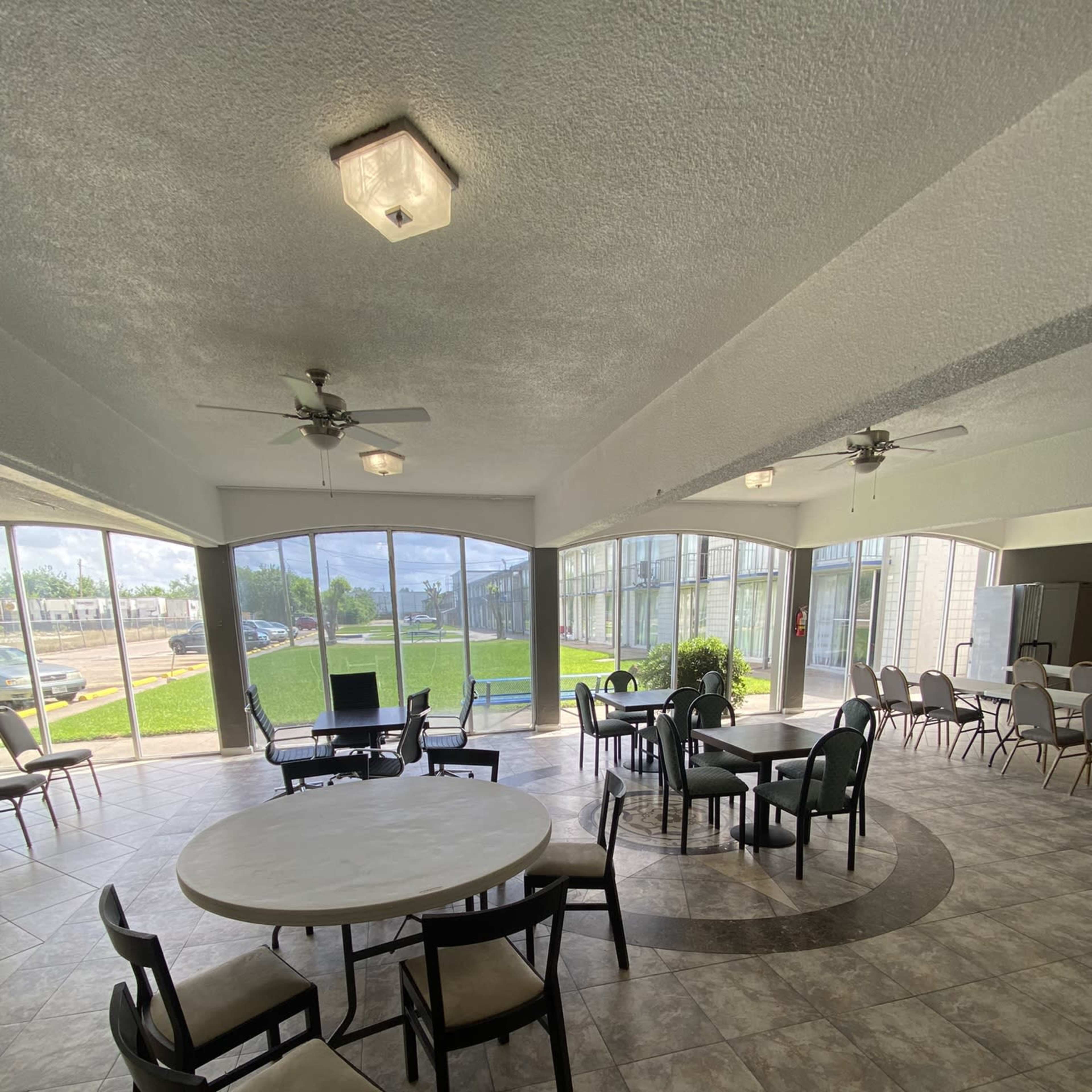 A spacious indoor seating area with tables and chairs, featuring large windows that provide a view of the outdoors.