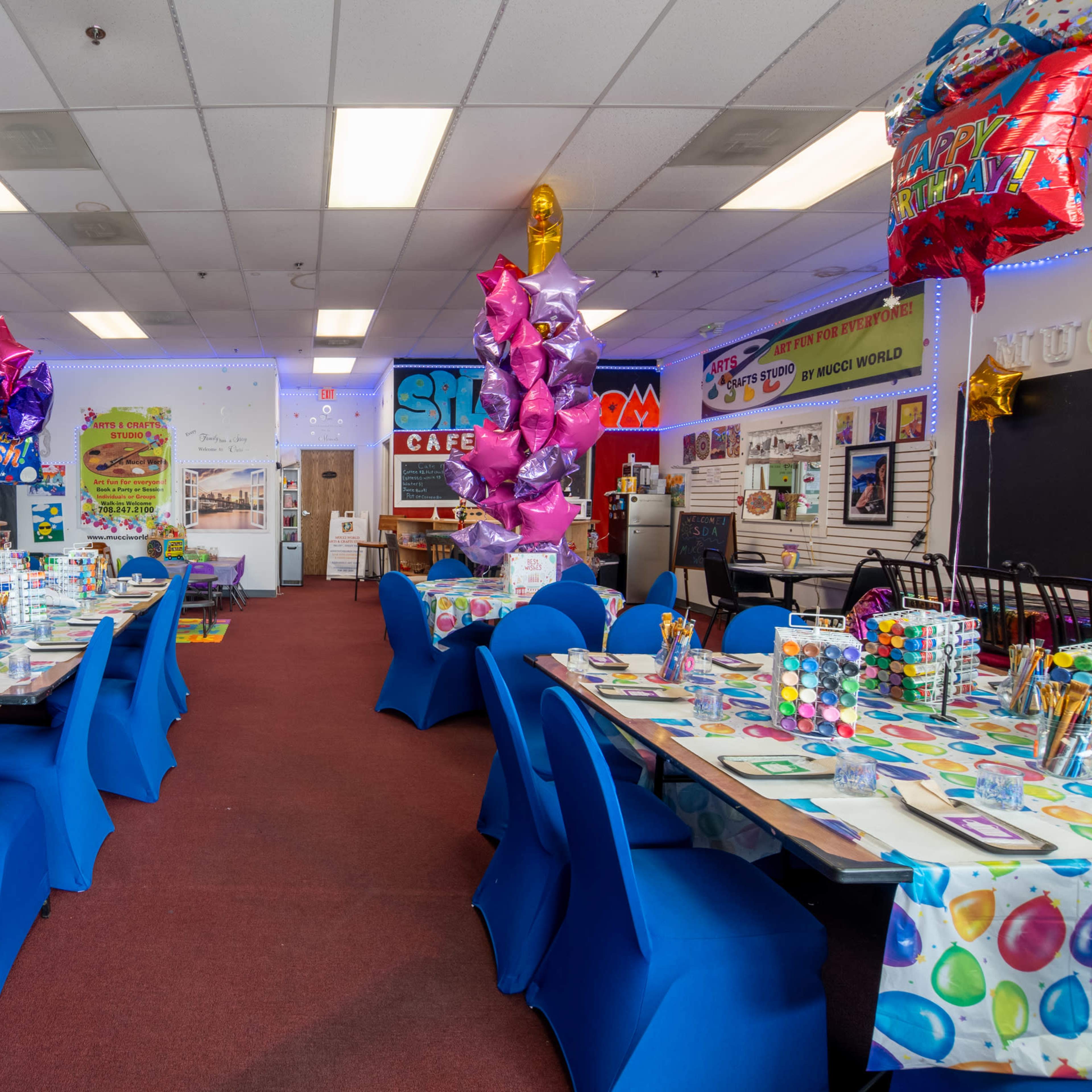 A brightly decorated cafe space features tables set with colorful items and balloons for a festive event.