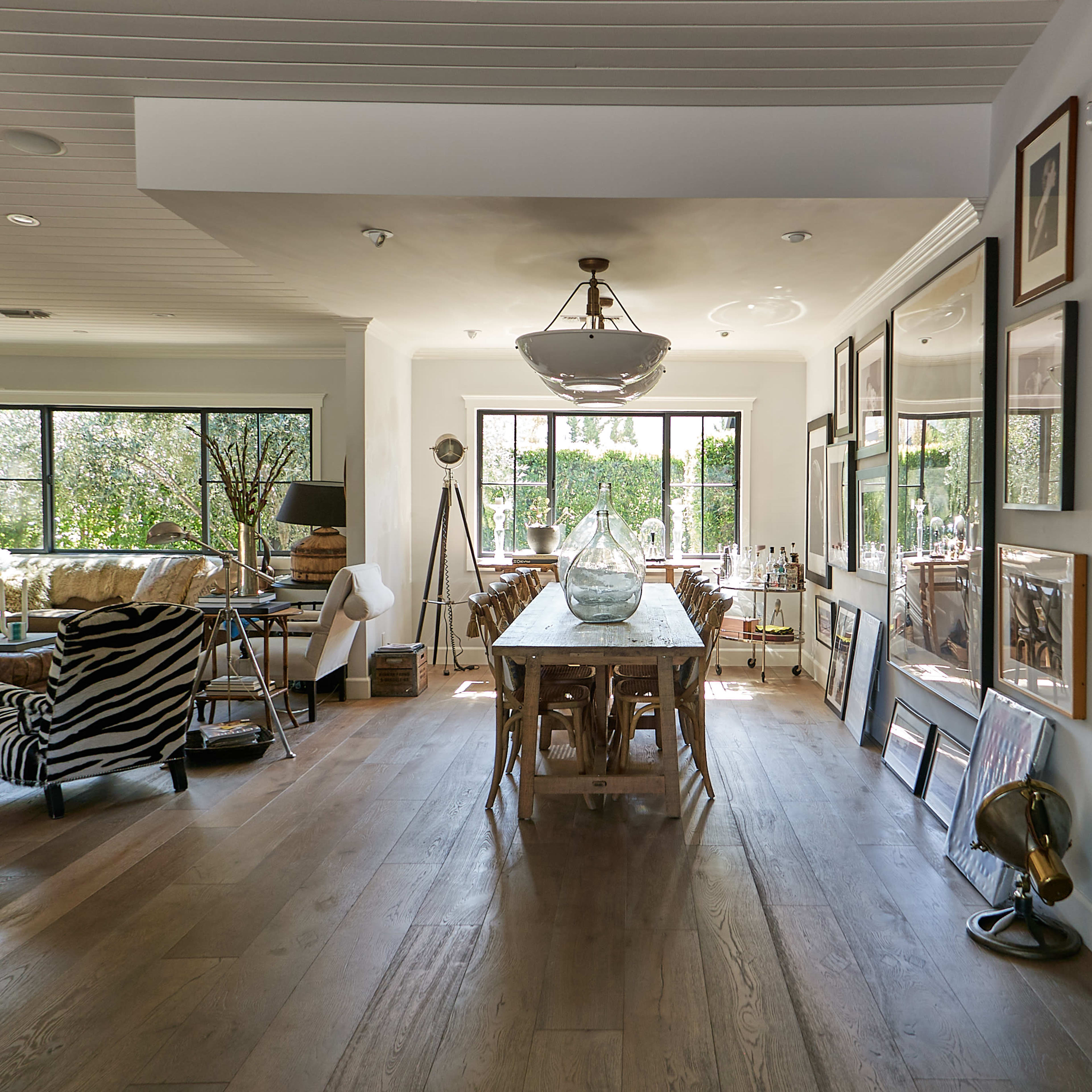 A spacious, modern living area featuring a dining table, a zebra-print chair, and large windows overlooking a garden.