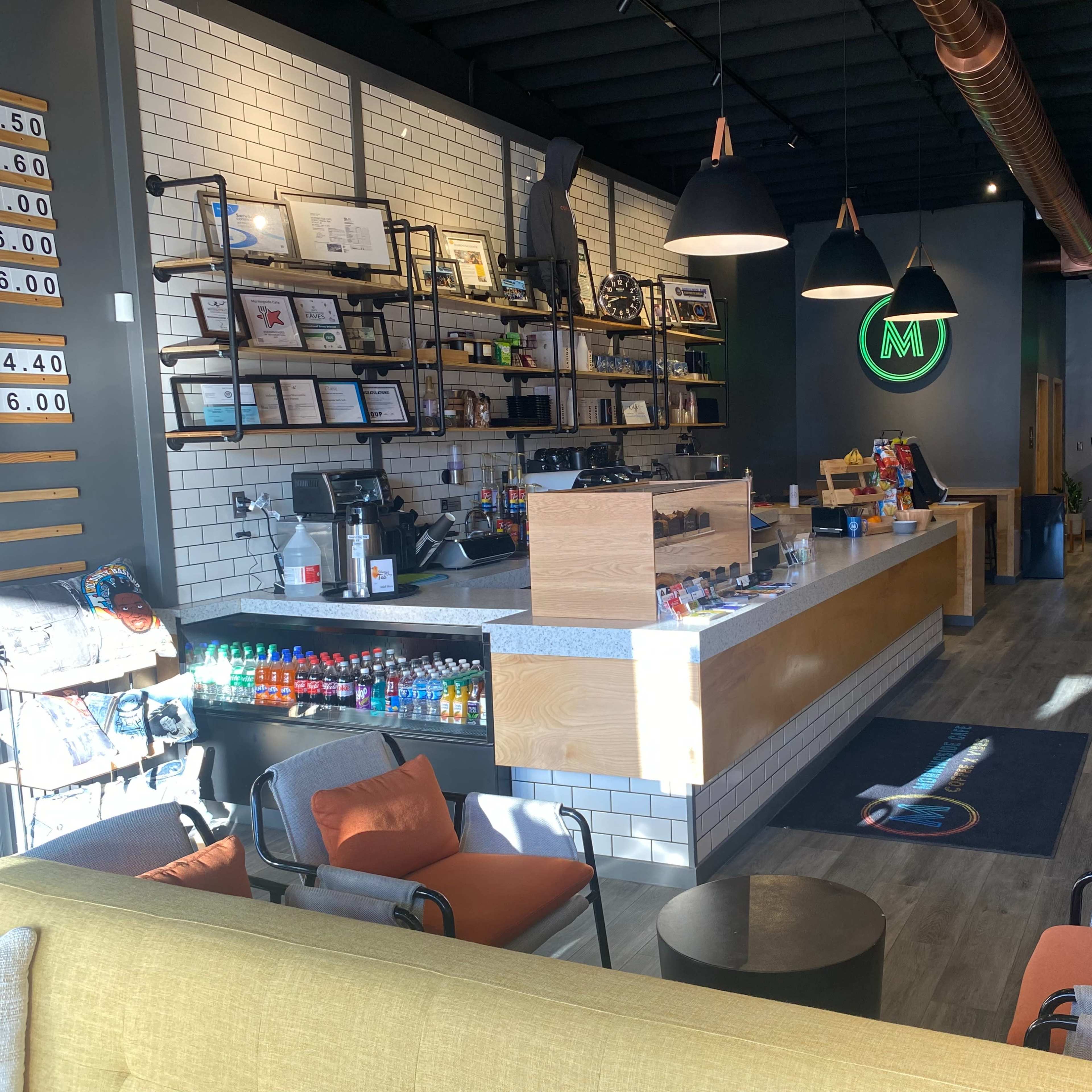 A modern café interior with a serving counter, seating areas, and a colorful mural on the wall.