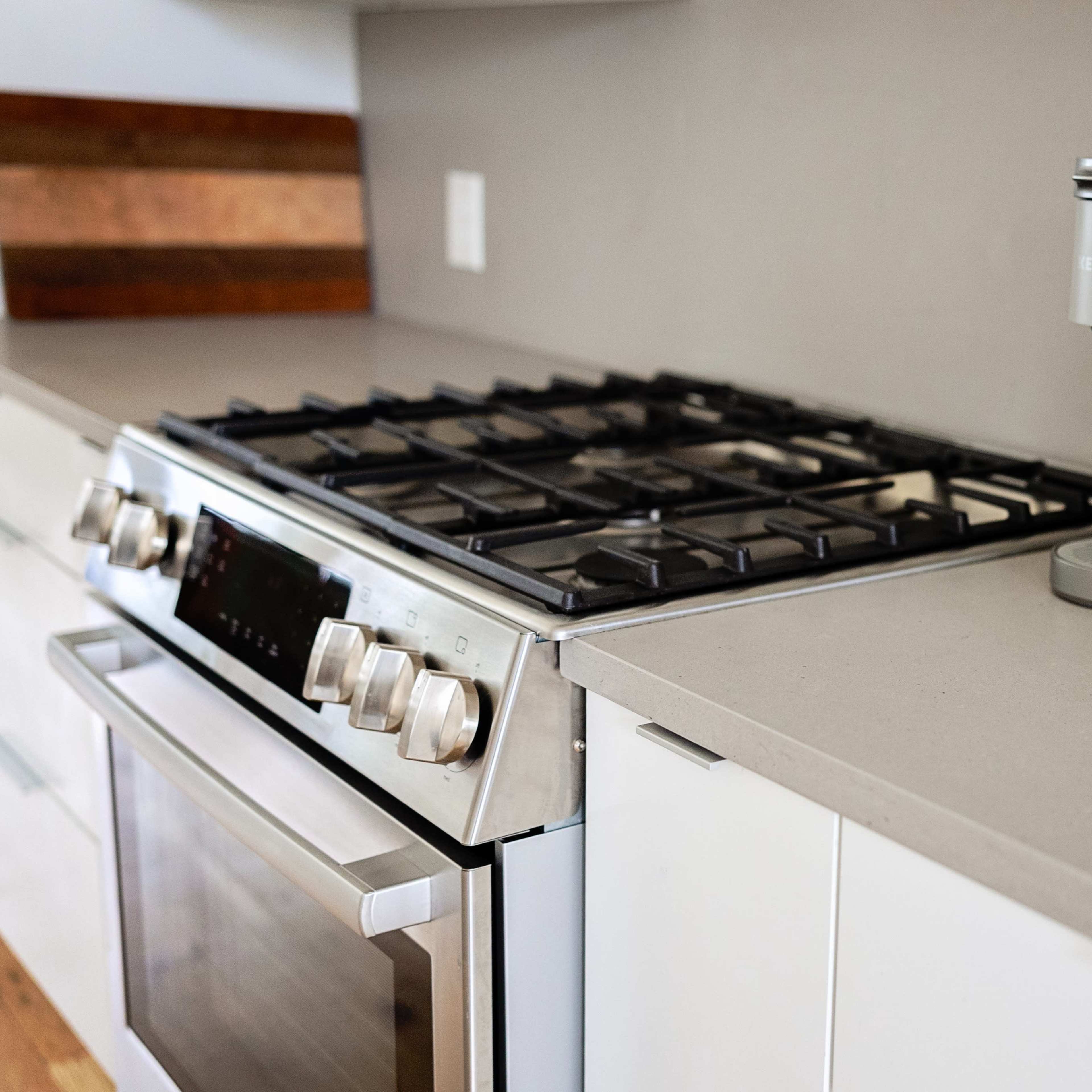 A kitchen countertop features a gas stove and a Keurig coffee maker alongside a cylindrical holder and a decorative dish.