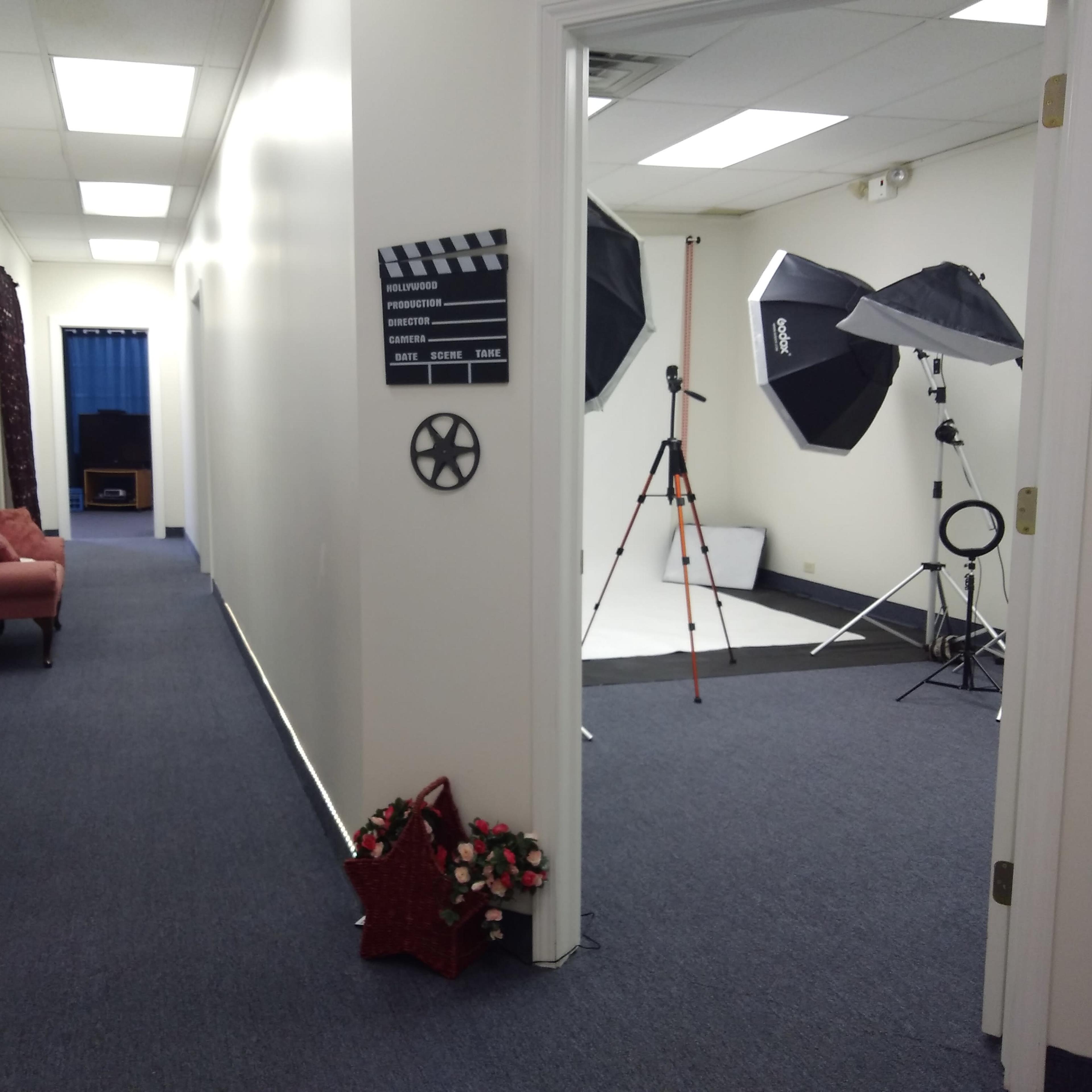 A hallway leading to a photography studio, with a sofa on one side and photography equipment set up on the other.