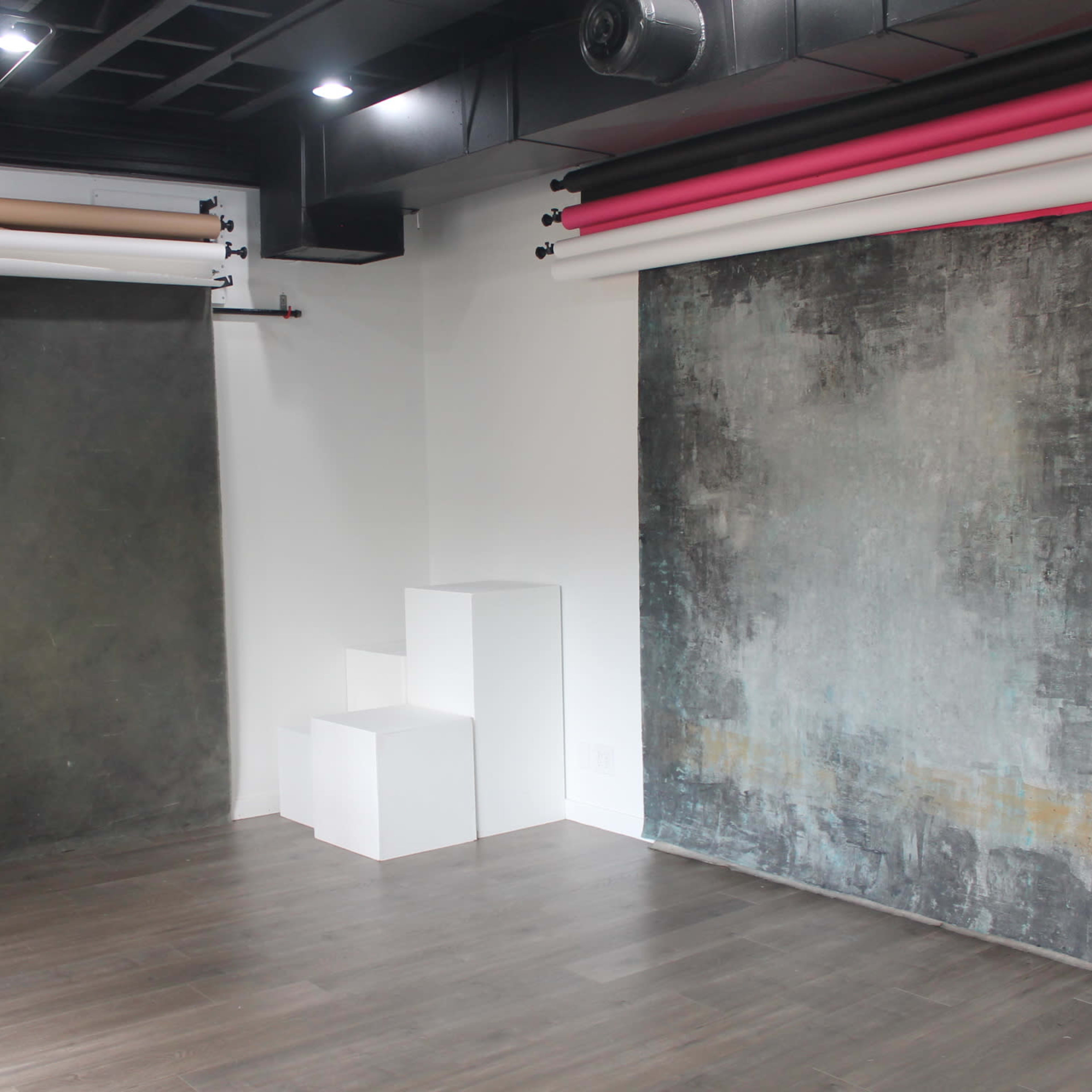 A photography studio with two large backdrop options on either side and white steps in the center.