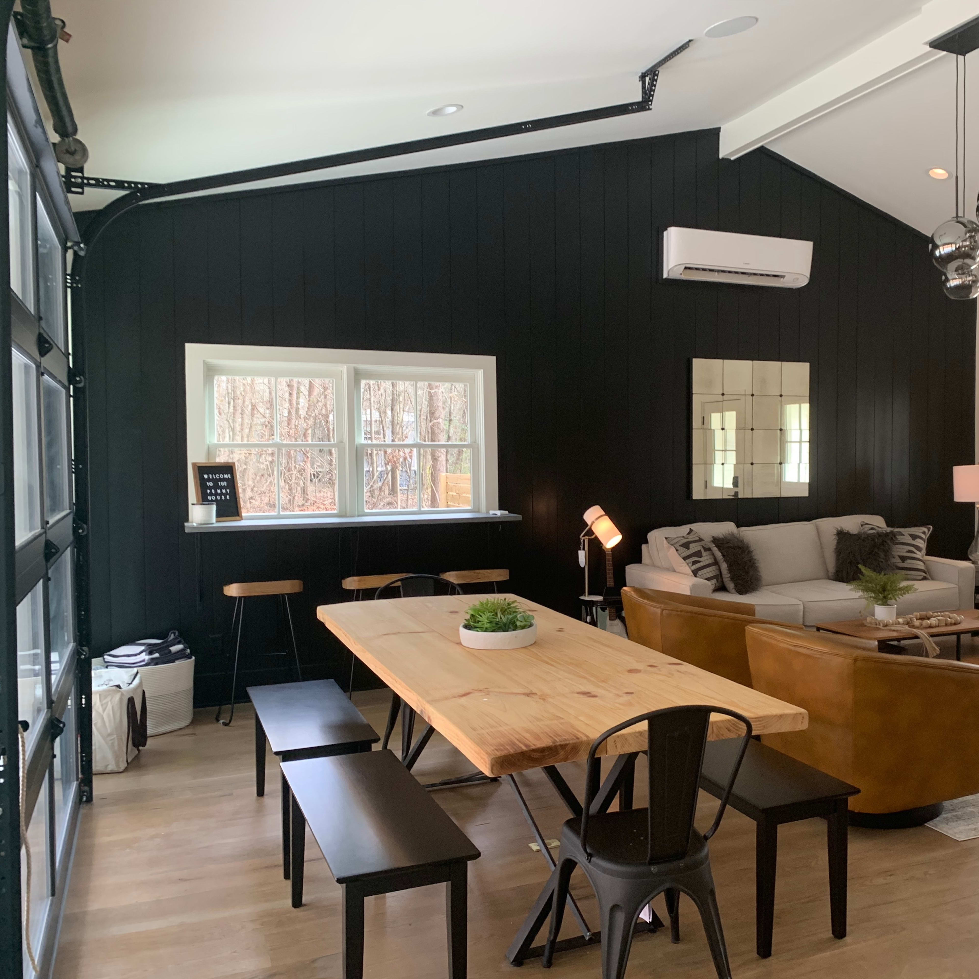 A modern living space featuring a dining table, seating area with a sofa, and large windows illuminating the room.