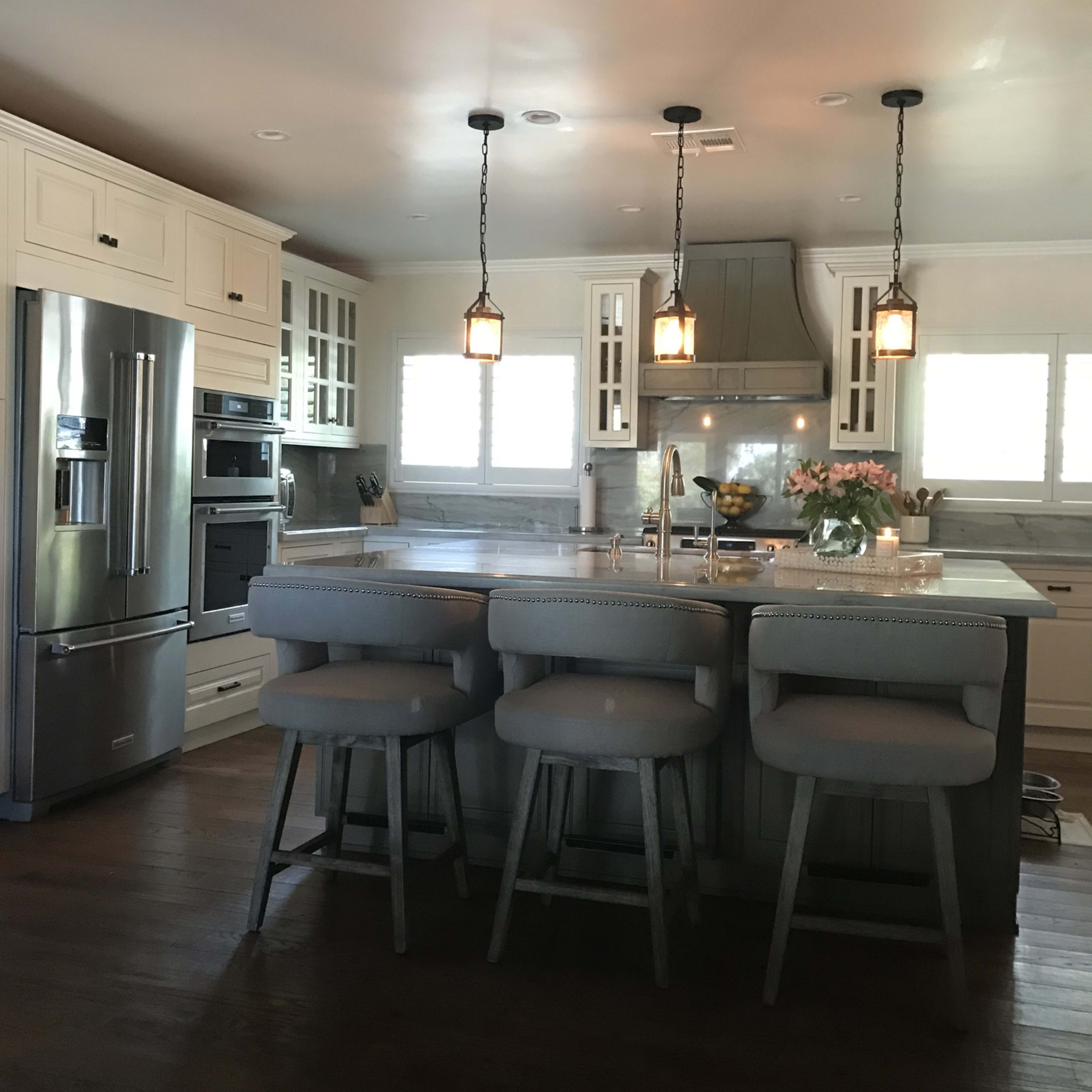 A modern kitchen featuring a central island with seating, stainless steel appliances, and pendant lighting.