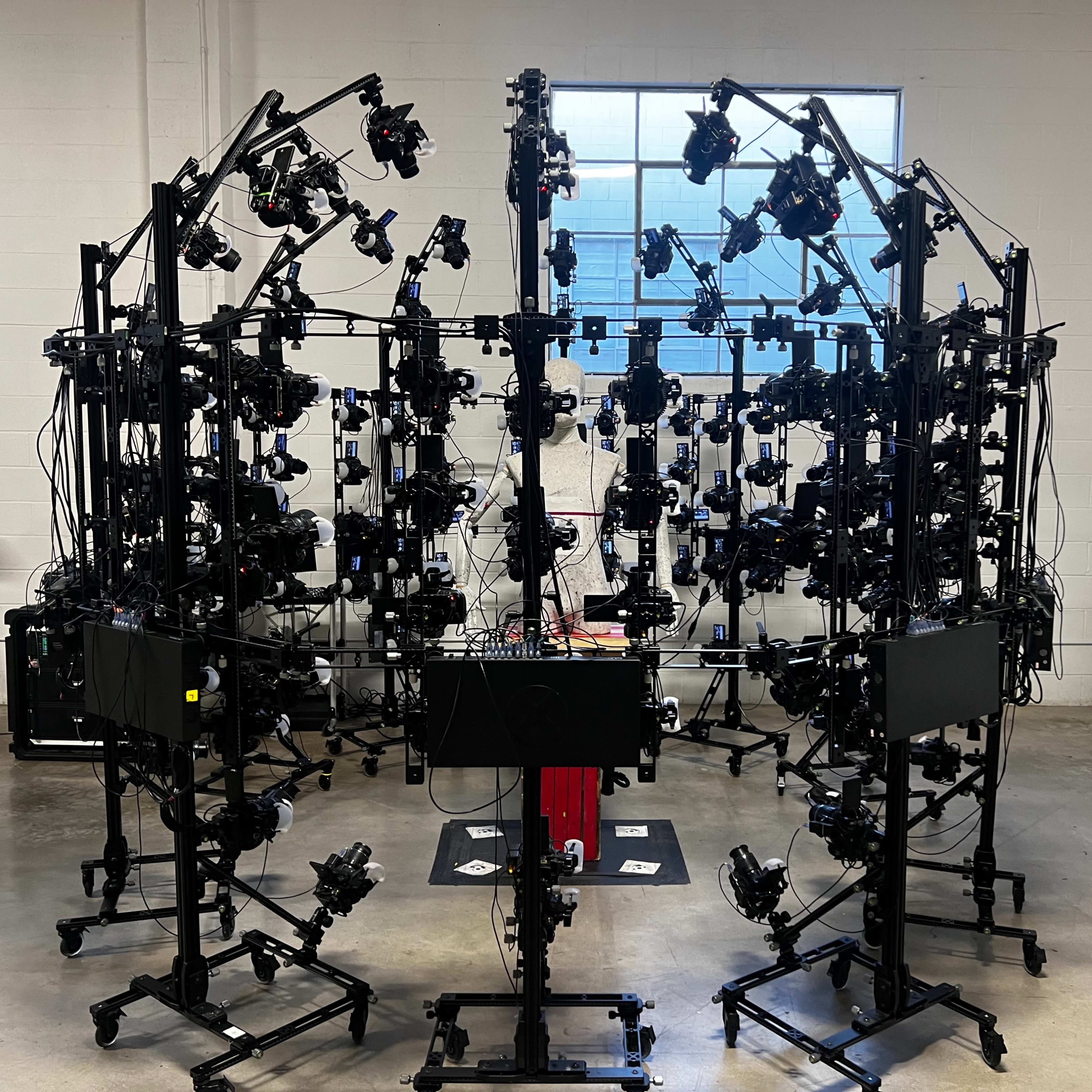 A series of cameras is arranged in a circular setup within a spacious industrial room.
