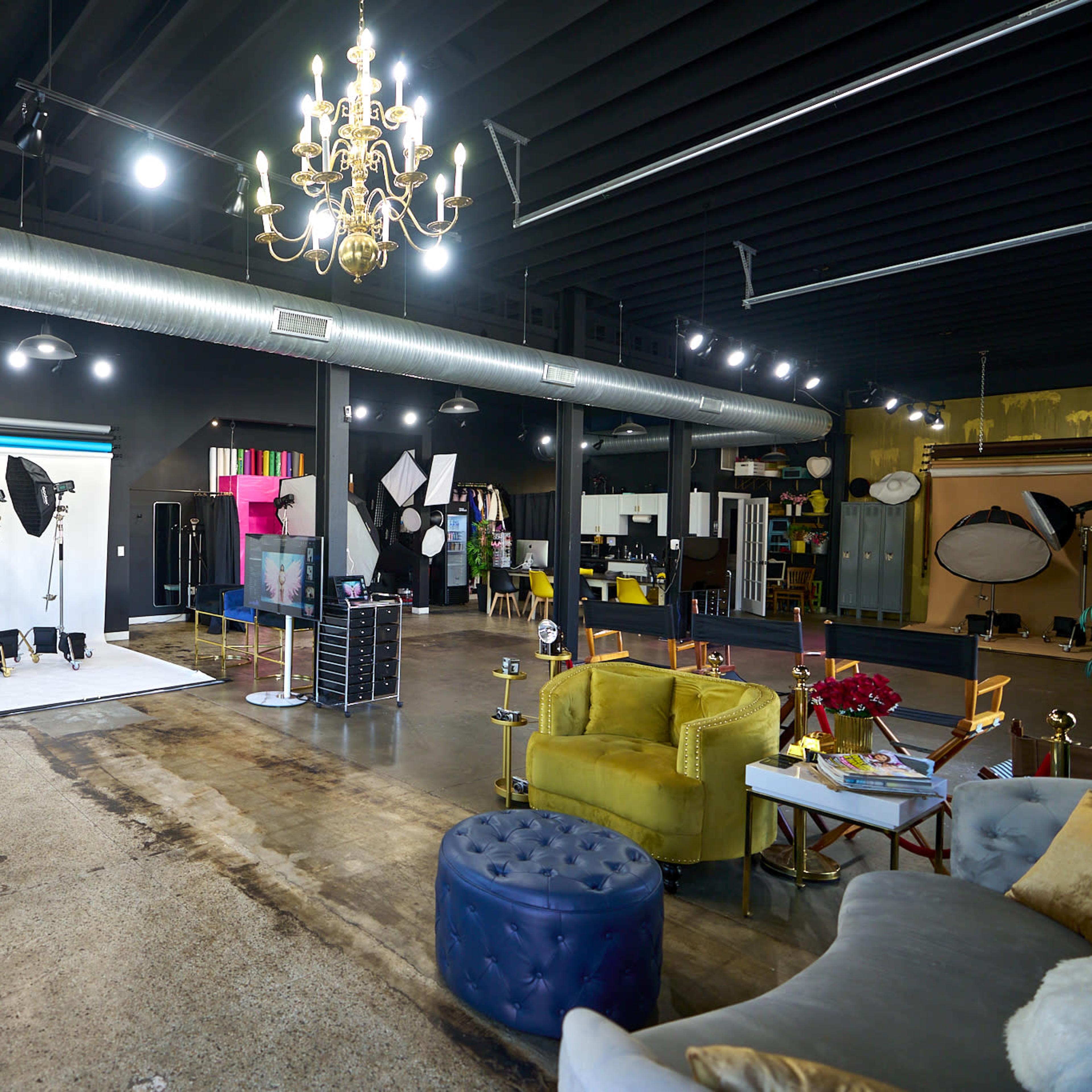 A spacious photography studio with various backdrops, lighting equipment, and seating areas.