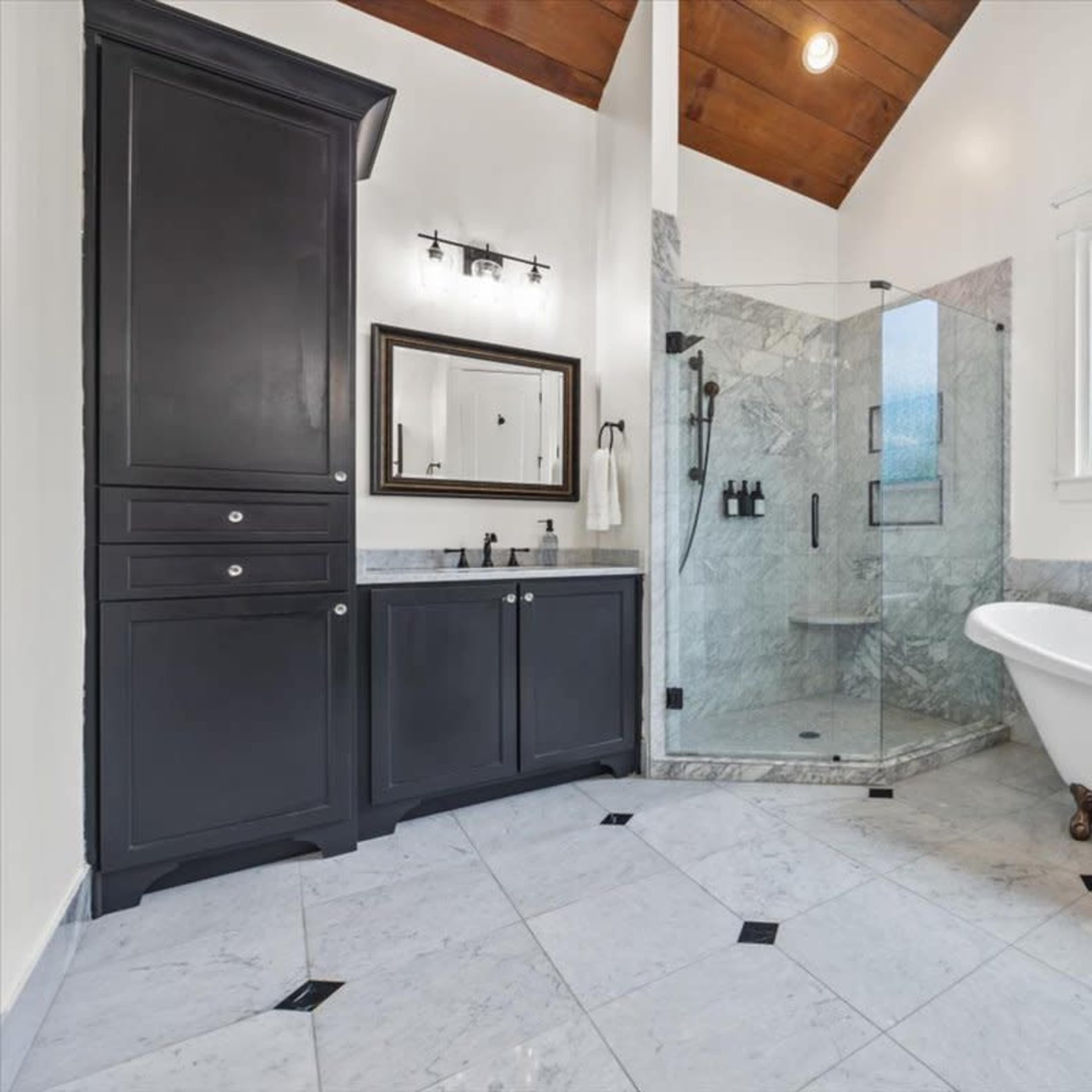 A bathroom featuring a freestanding bathtub, a glass shower enclosure, and marble flooring.