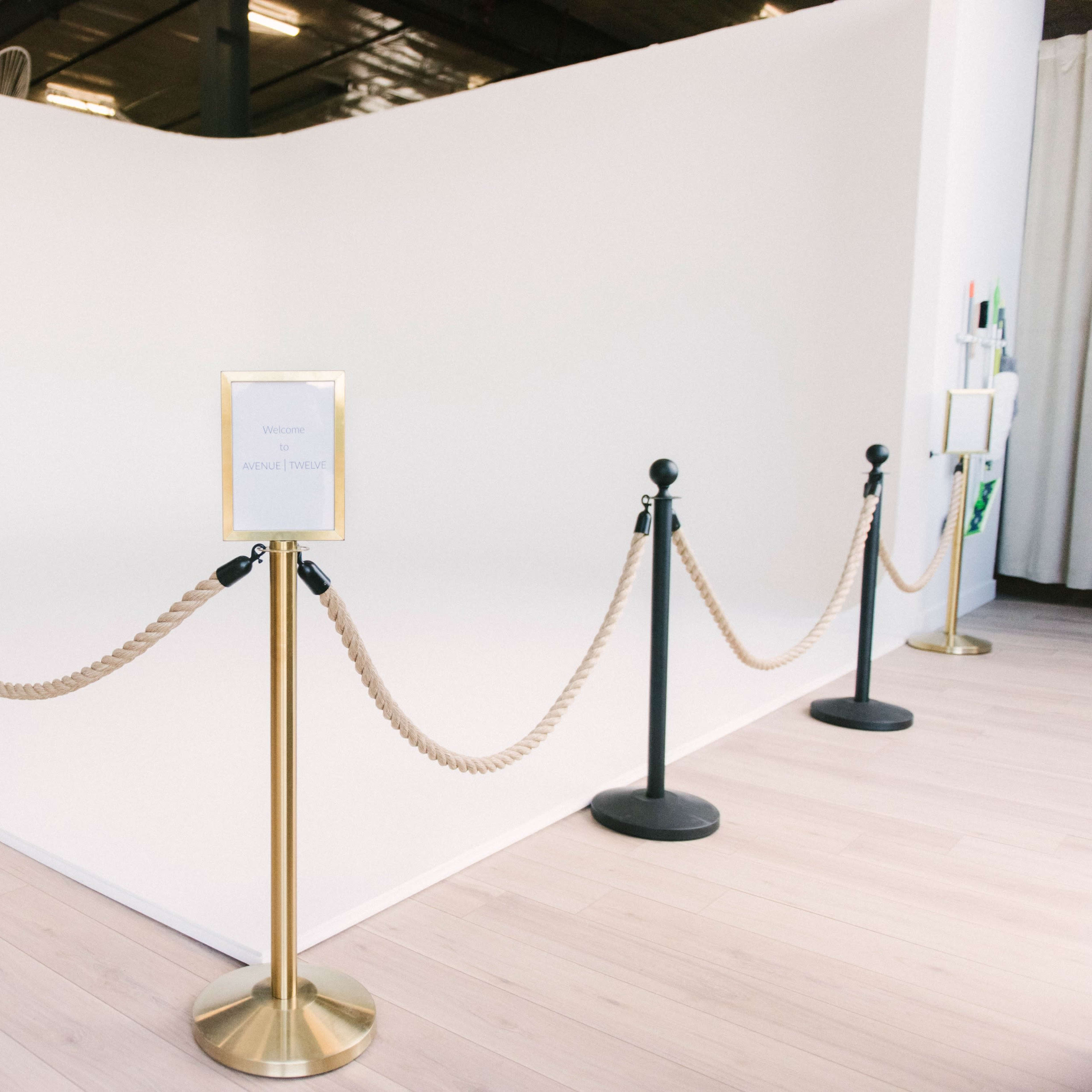 A white backdrop area surrounded by black stanchions and a rope barrier, with a sign indicating "Welcome" at the entrance.