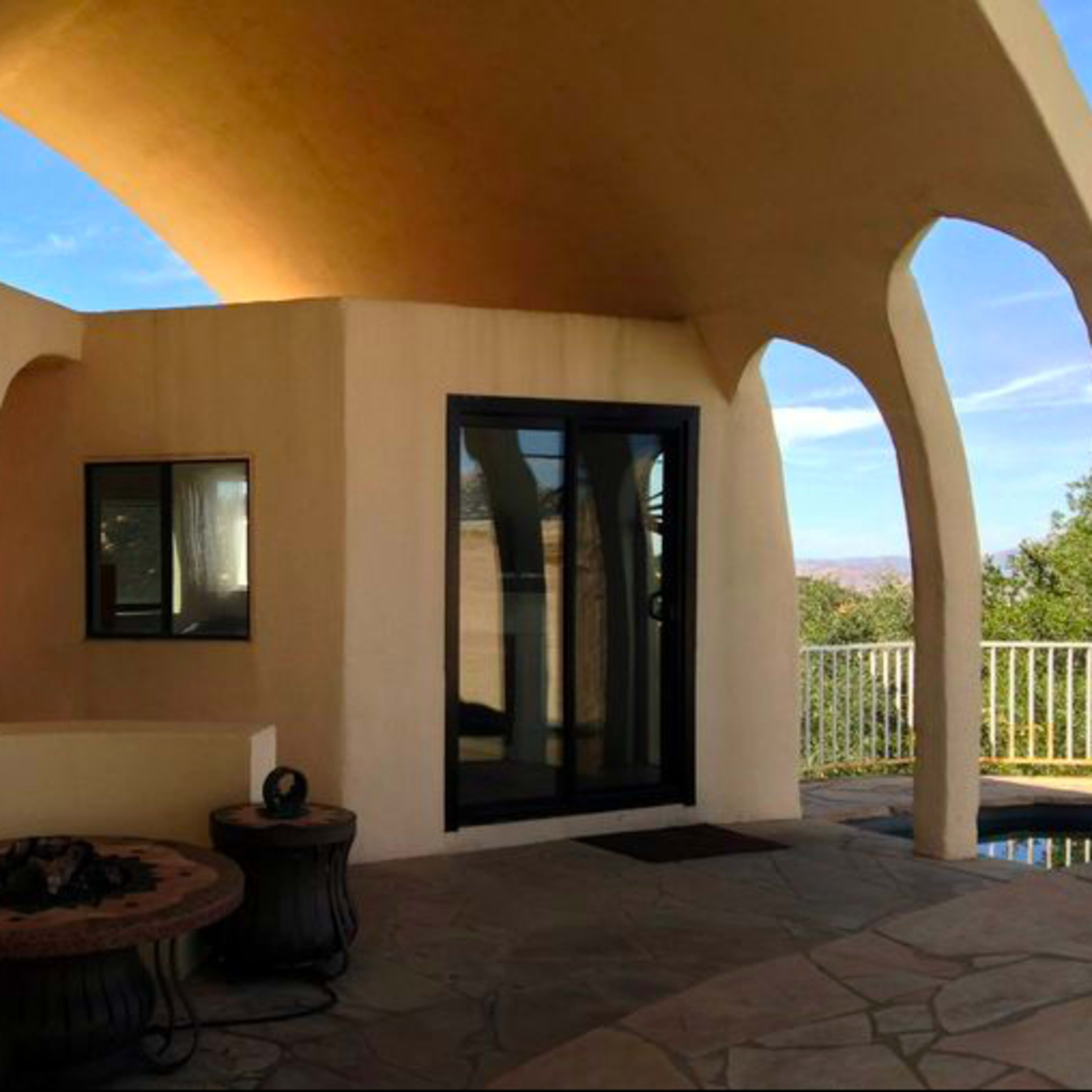 A modern architectural interior with a curved ceiling, a staircase leading up, and a large glass door opening to an outdoor view.