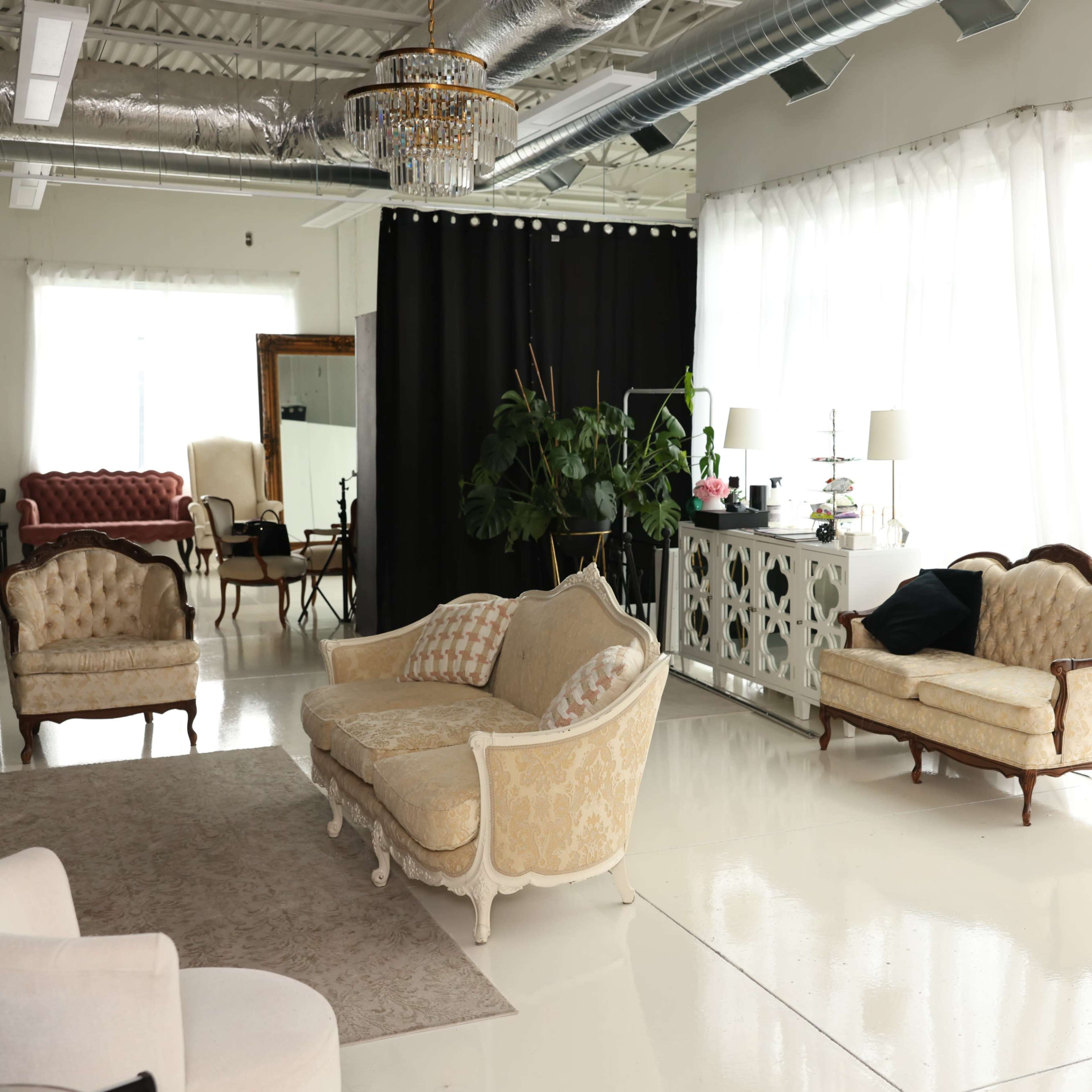 A bright, modern interior with elegant furniture, large windows, and a decorative mannequin adorned with feathered wings.
