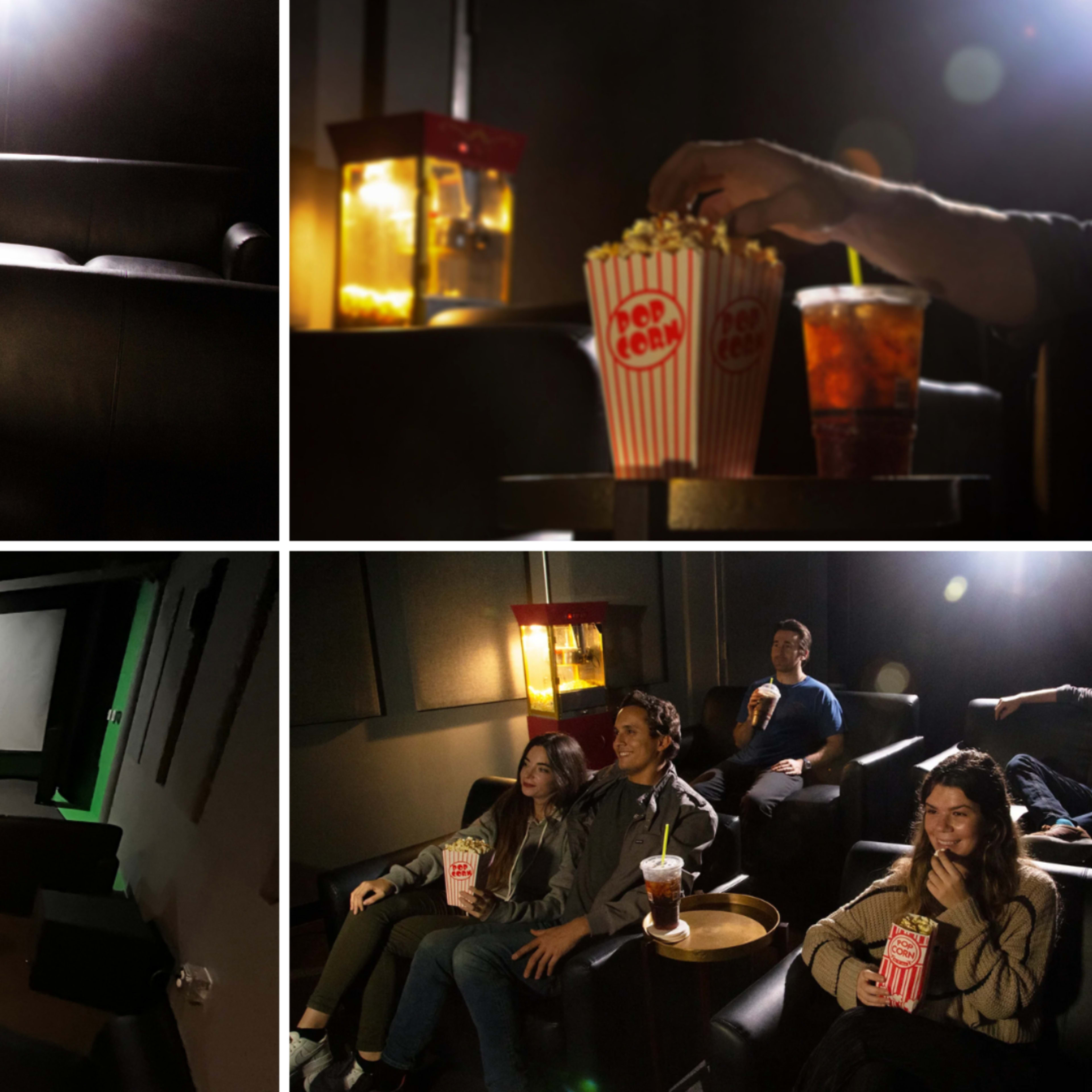 A home theater with empty seats, a popcorn machine, and four people enjoying snacks in front of a large screen.