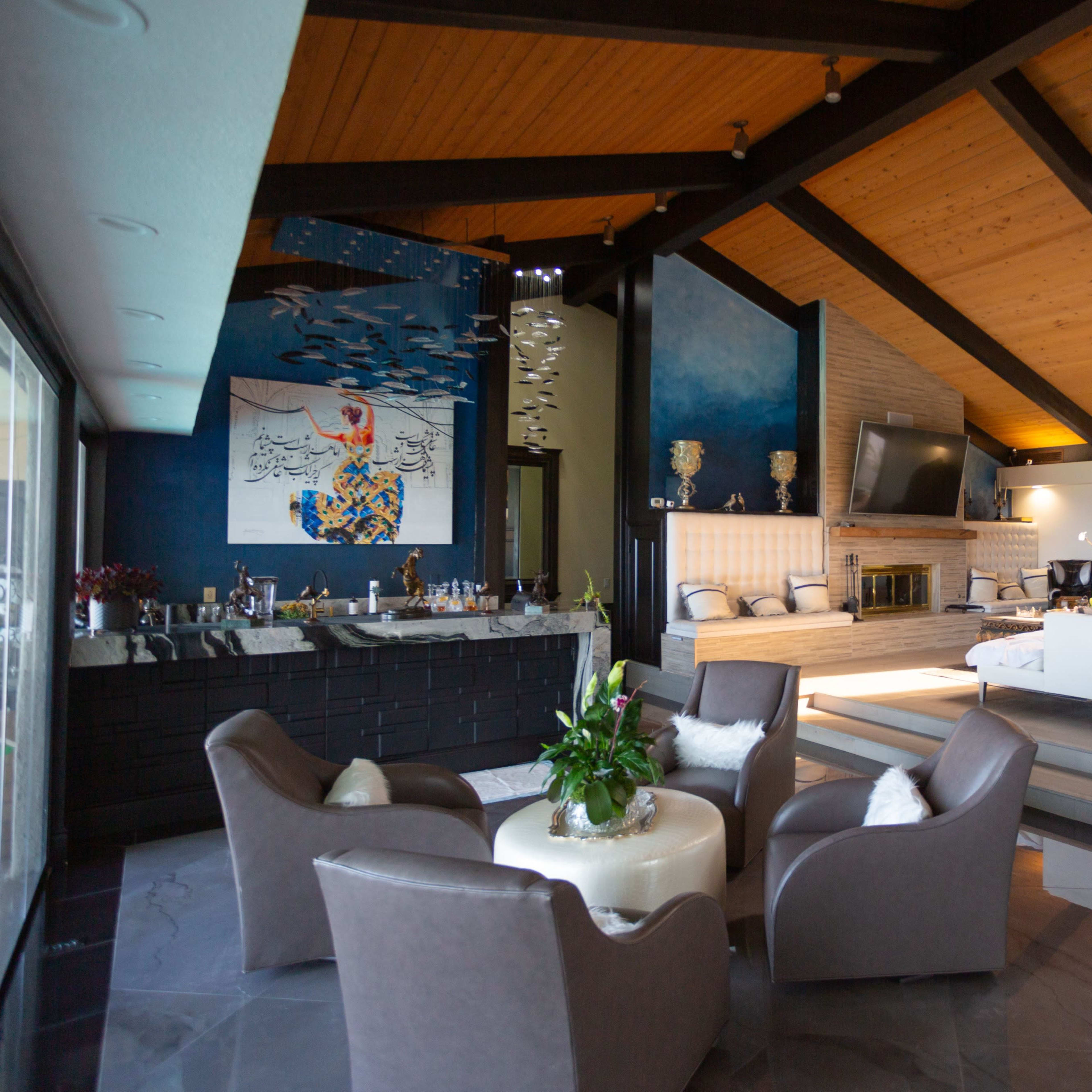 A spacious, modern living room with a high wooden ceiling, a large seating area, and an artistic mural on the blue wall.