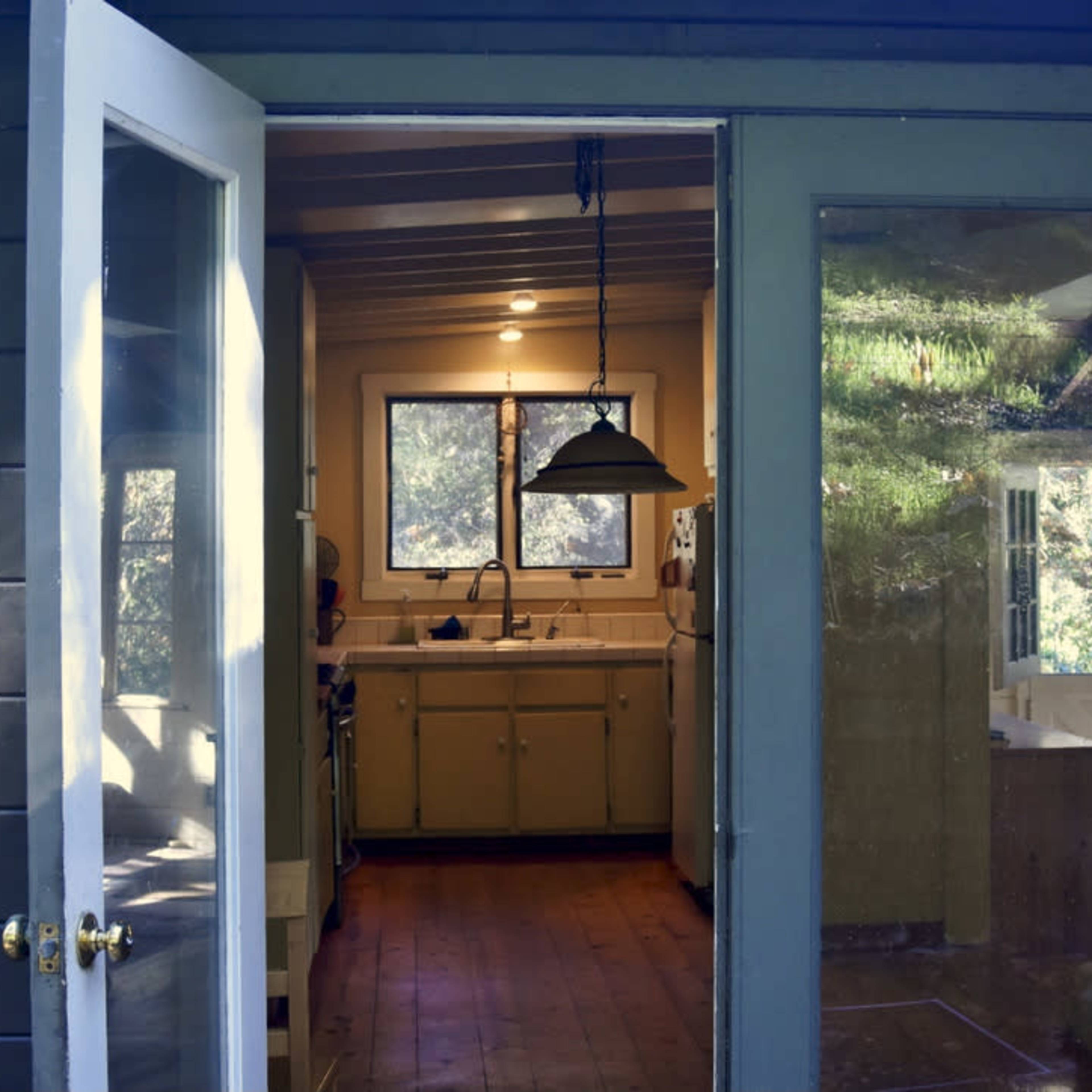 An open door leading into a kitchen with yellow cabinetry and a window providing natural light.