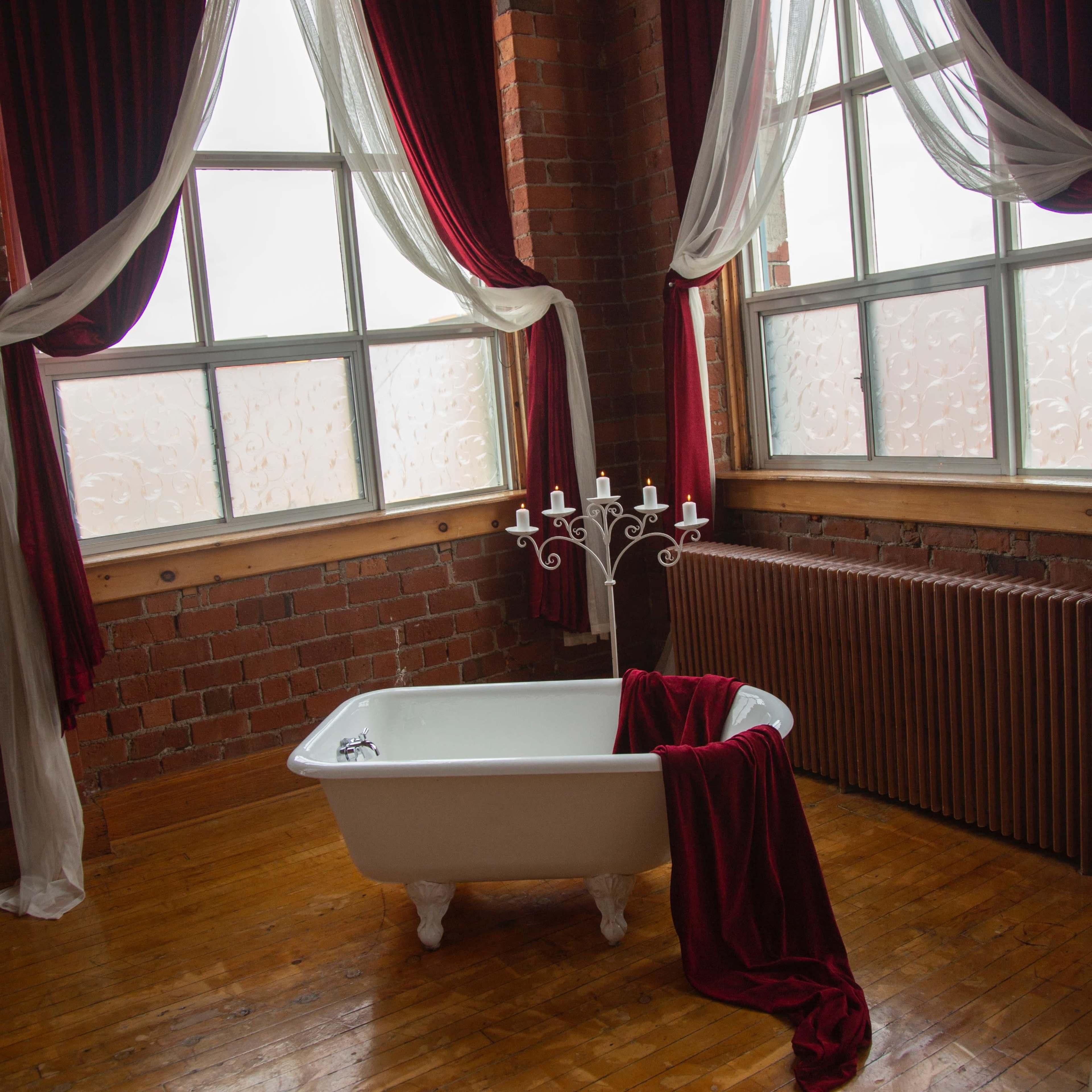 A spacious industrial-style room with exposed brick walls, large windows, and a mix of modern and vintage furniture.