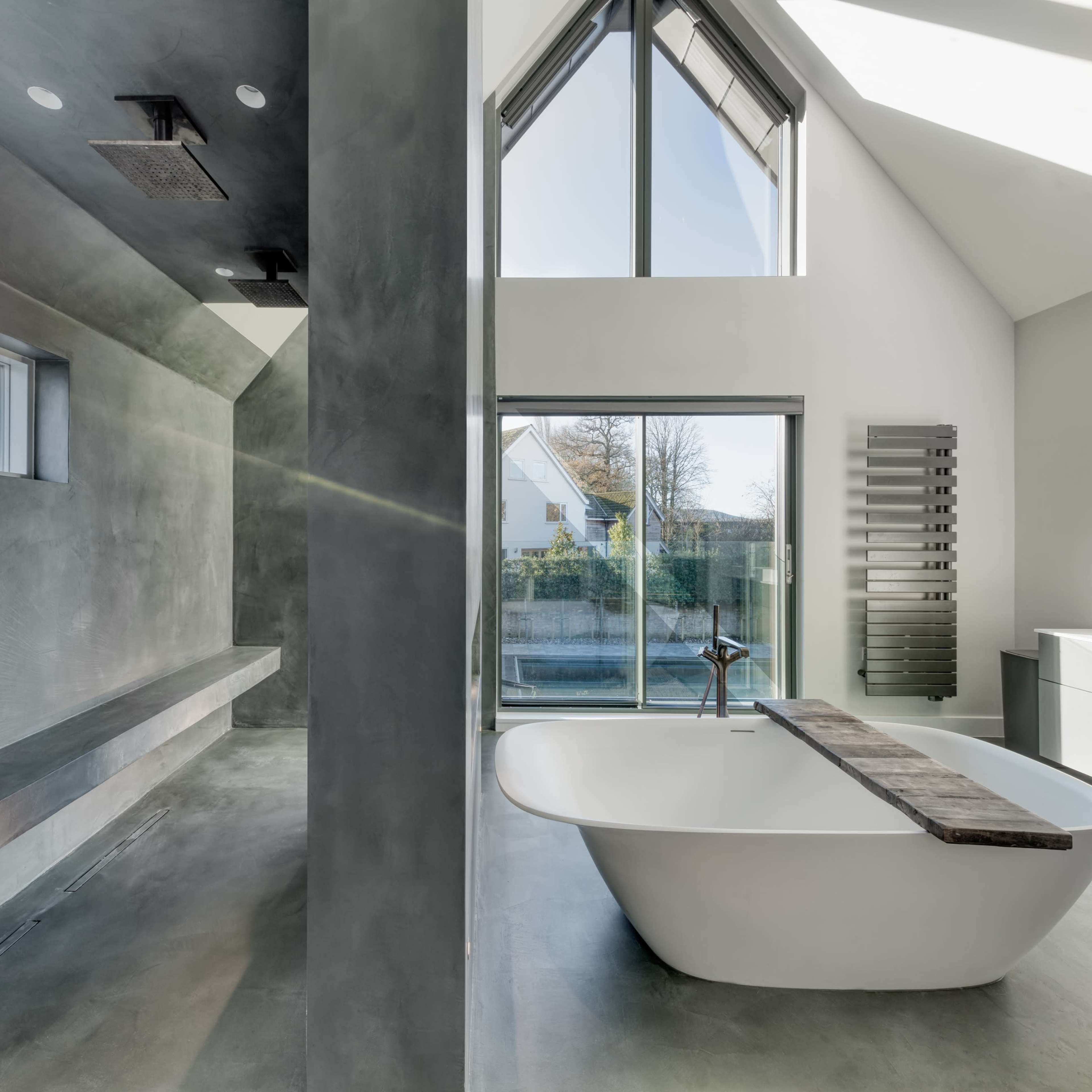 A modern bathroom featuring a freestanding bathtub, large windows, and minimalist design elements.
