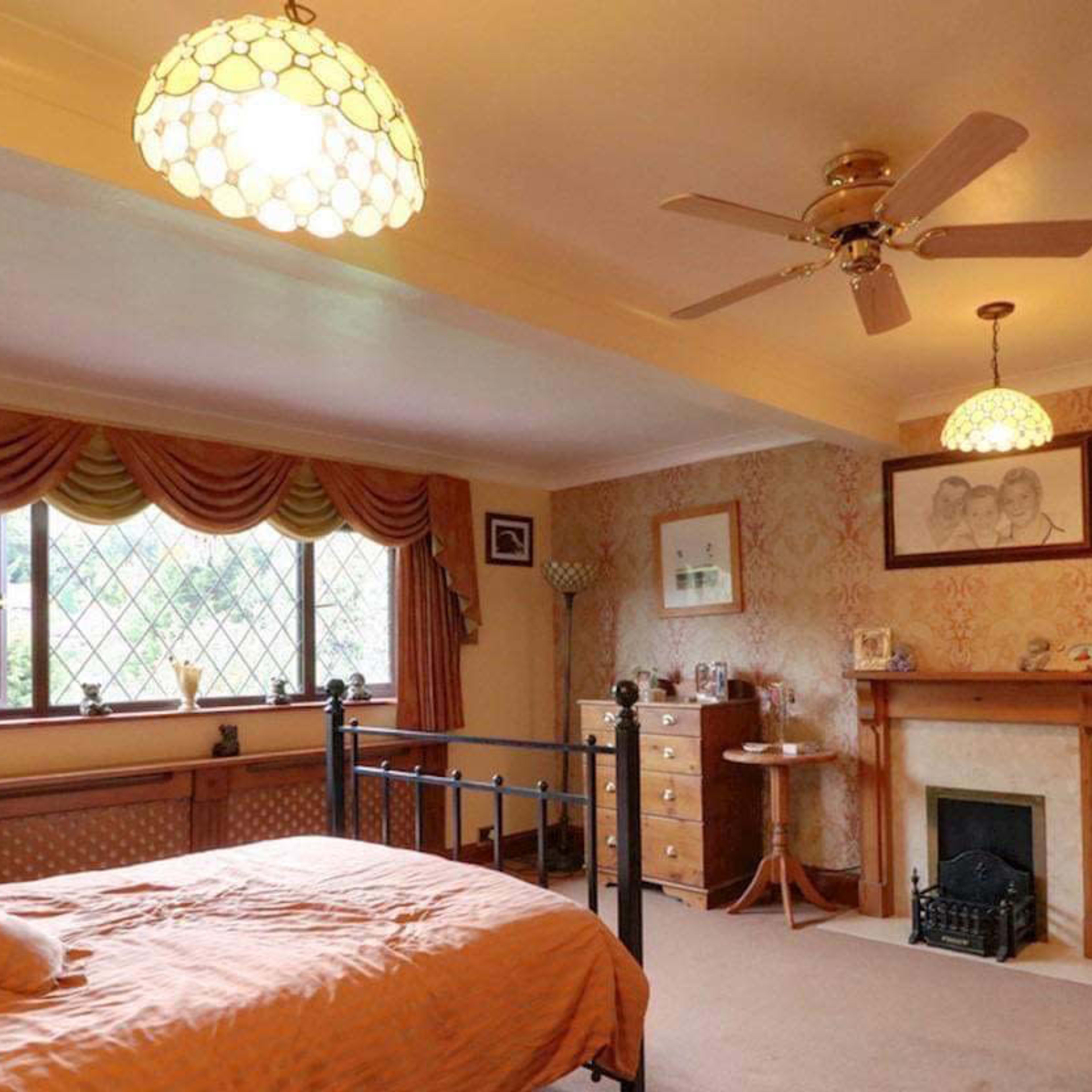 A spacious bedroom with a double bed, a fireplace, and a large window adorned with curtains.