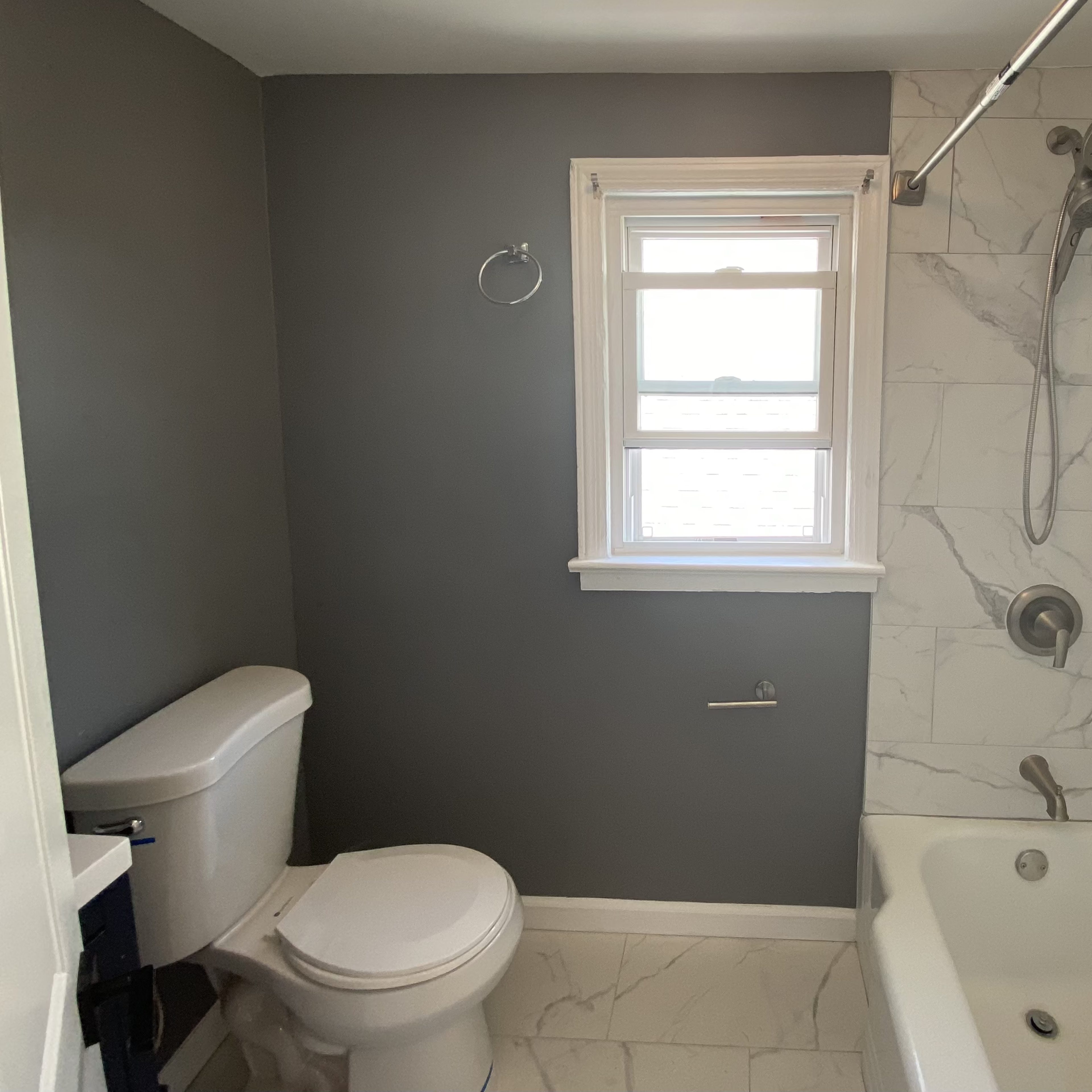 A bathroom with a shower, bathtub, toilet, and a window allowing natural light.