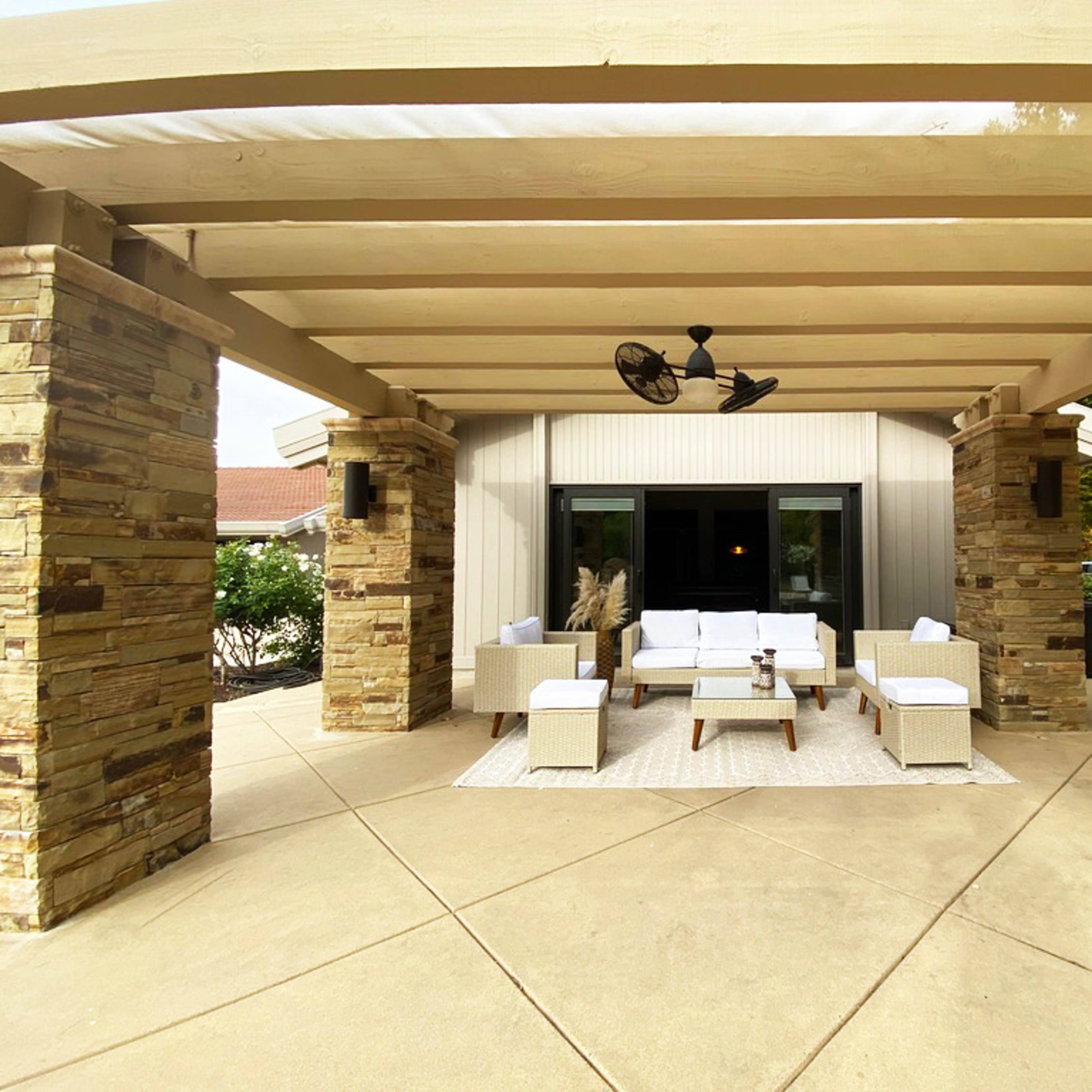 A backyard pool area surrounded by trees, lounge chairs, and a covered seating space.