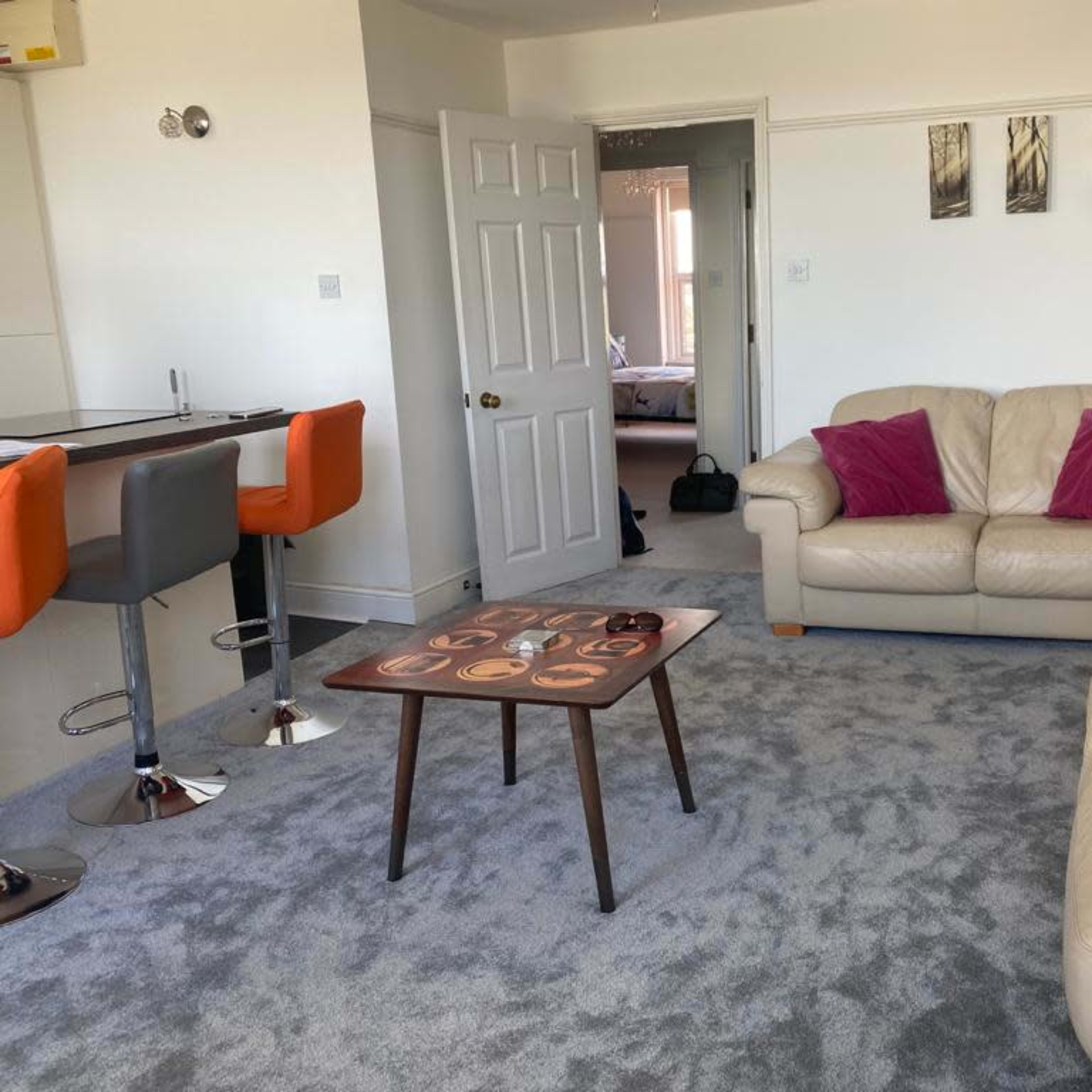 A living room with two leather sofas, a wooden coffee table, and a bar area with high stools.