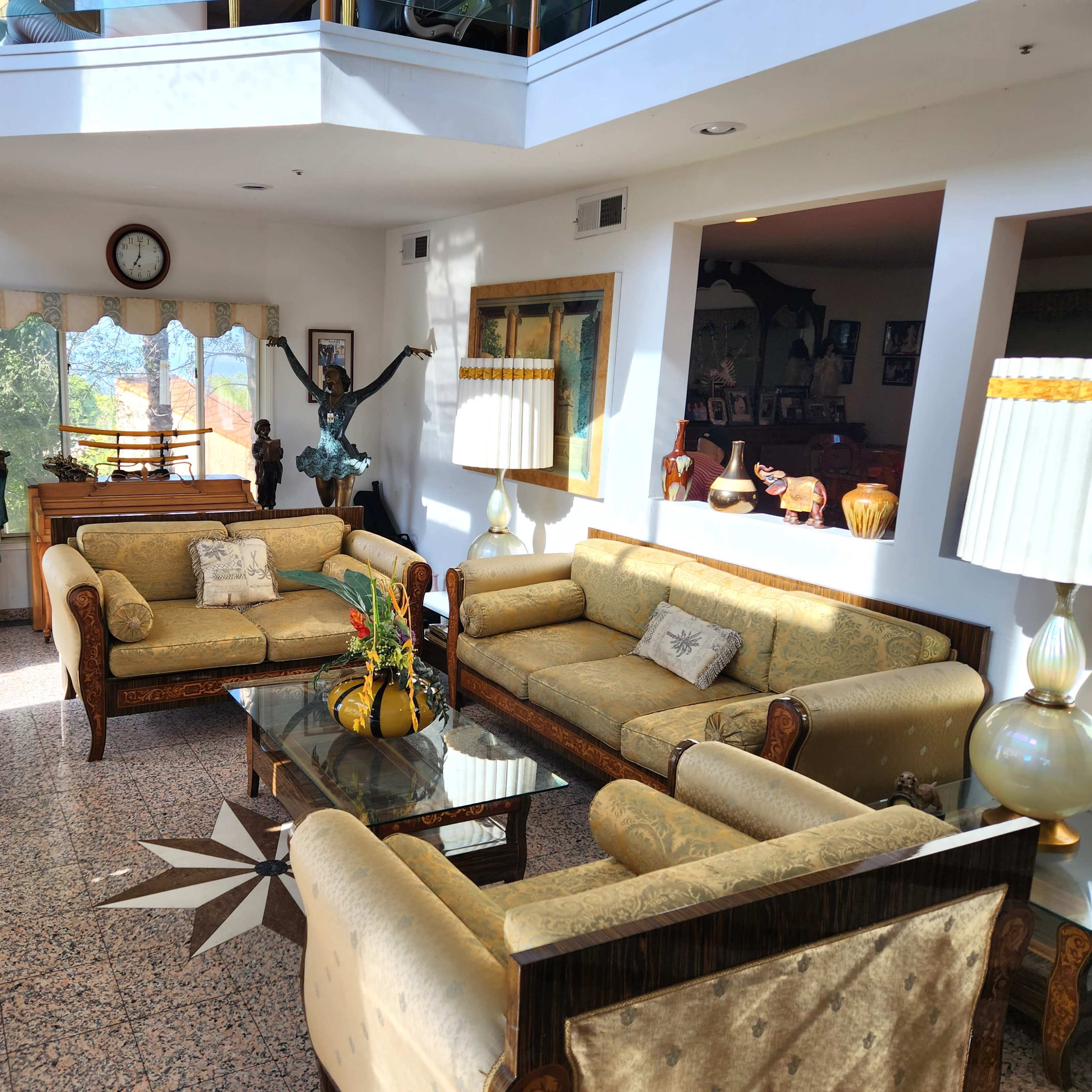 The living room features ornate furniture, a fireplace, and large windows that allow natural light to illuminate the space.