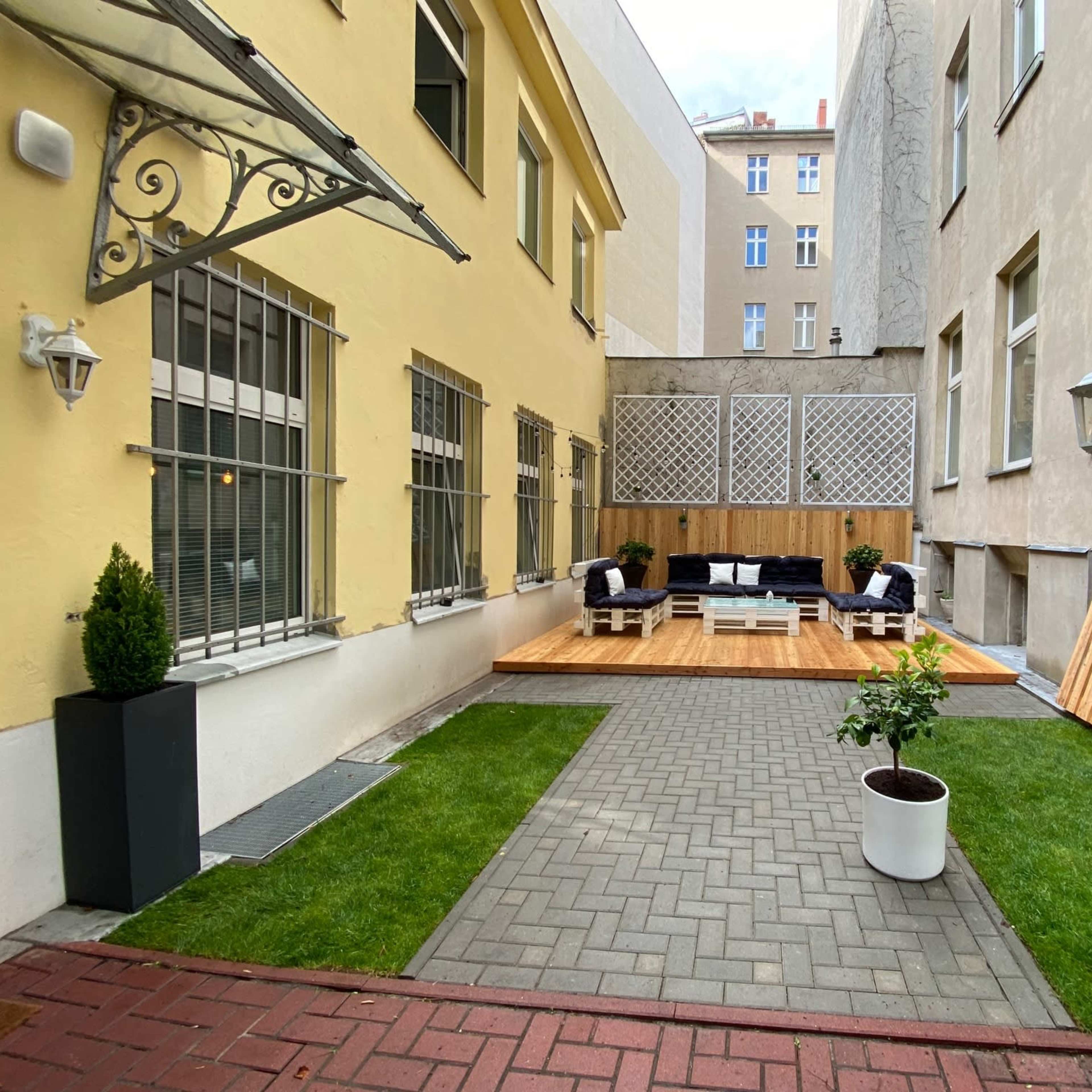A courtyard area with a wooden deck, outdoor seating, landscaped grass, and a decorative lamp post.