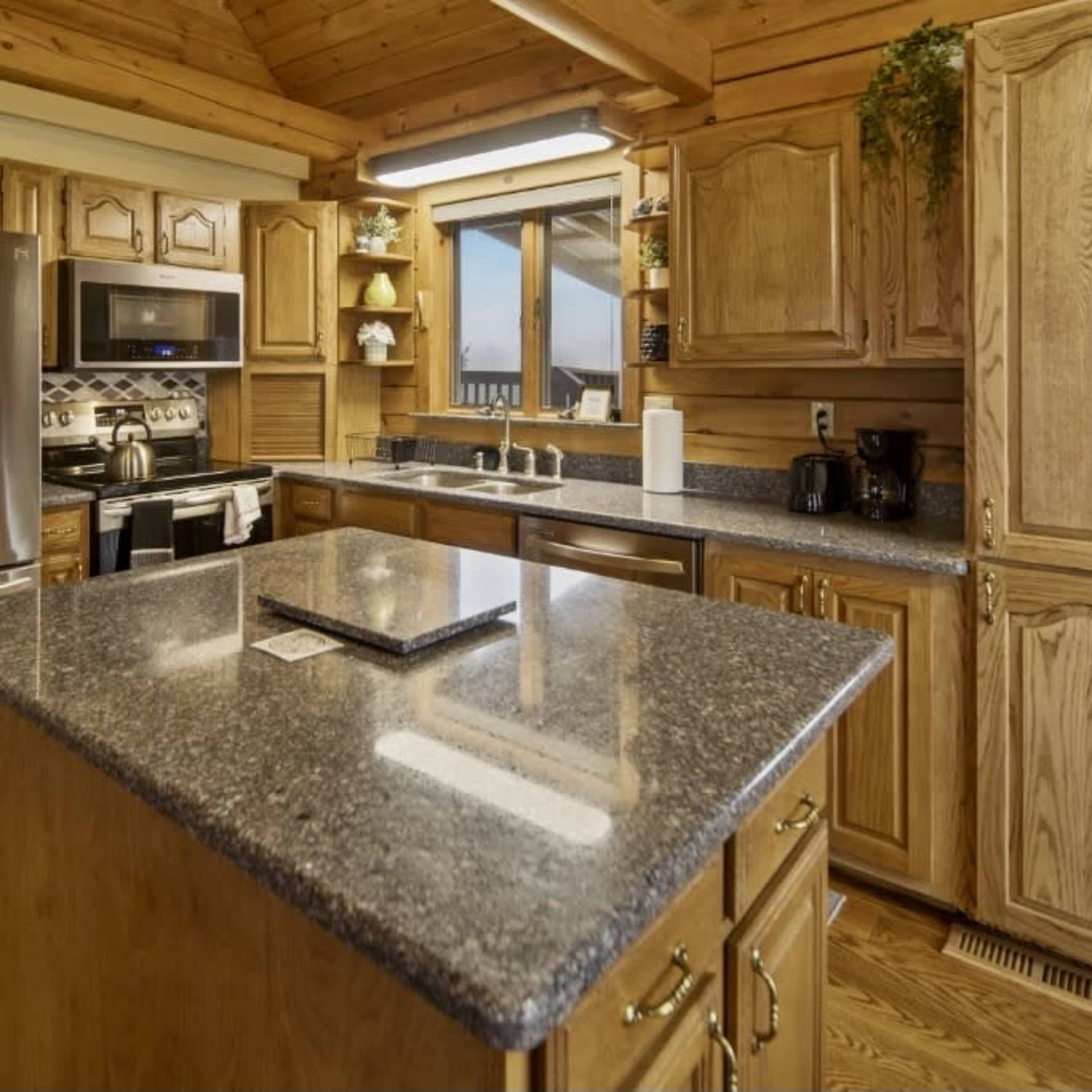 A well-organized kitchen featuring wooden cabinets, a central island with a granite countertop, and stainless steel appliances.