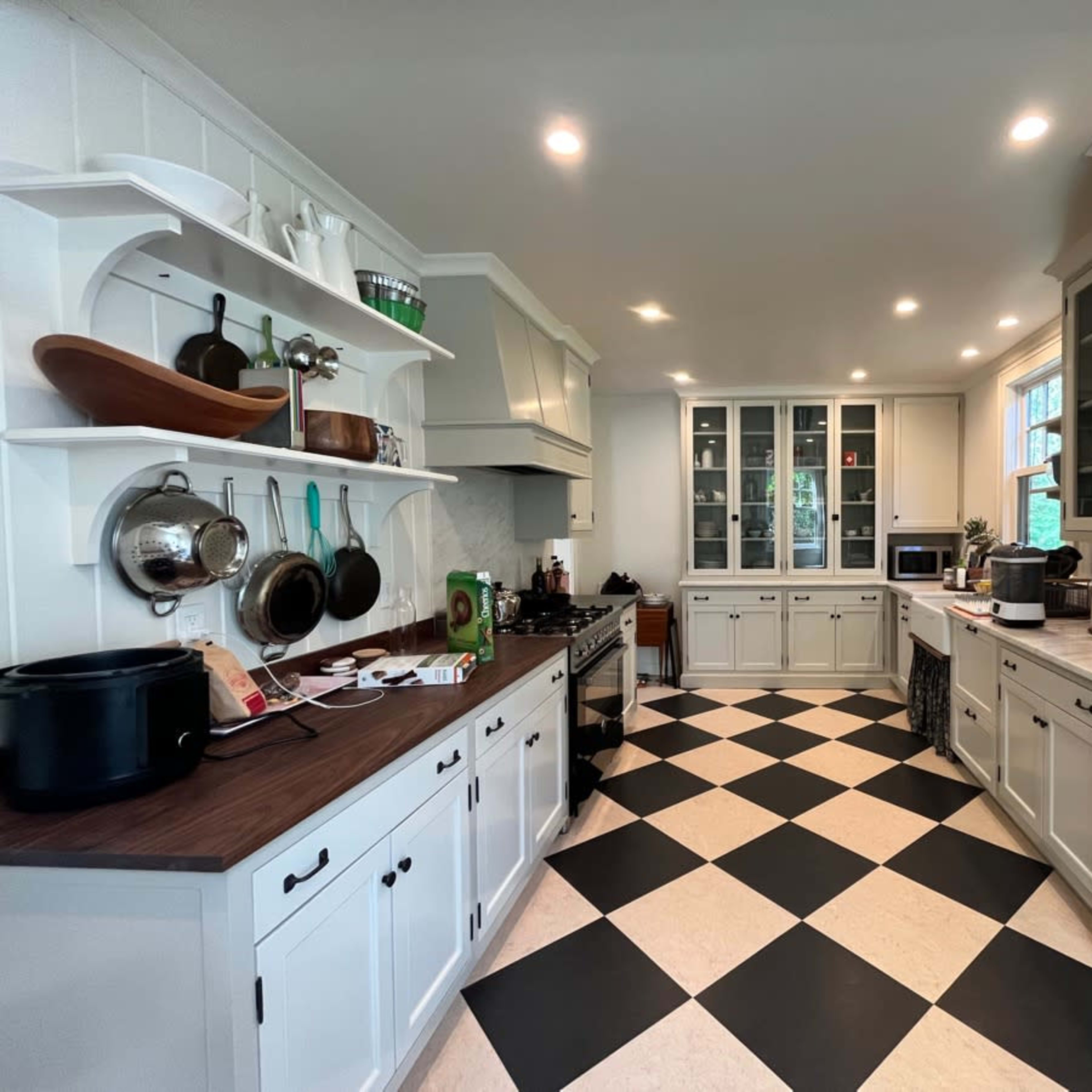 A kitchen with white cabinetry, a black and white checkered floor, and a mix of open shelving and closed cabinets.