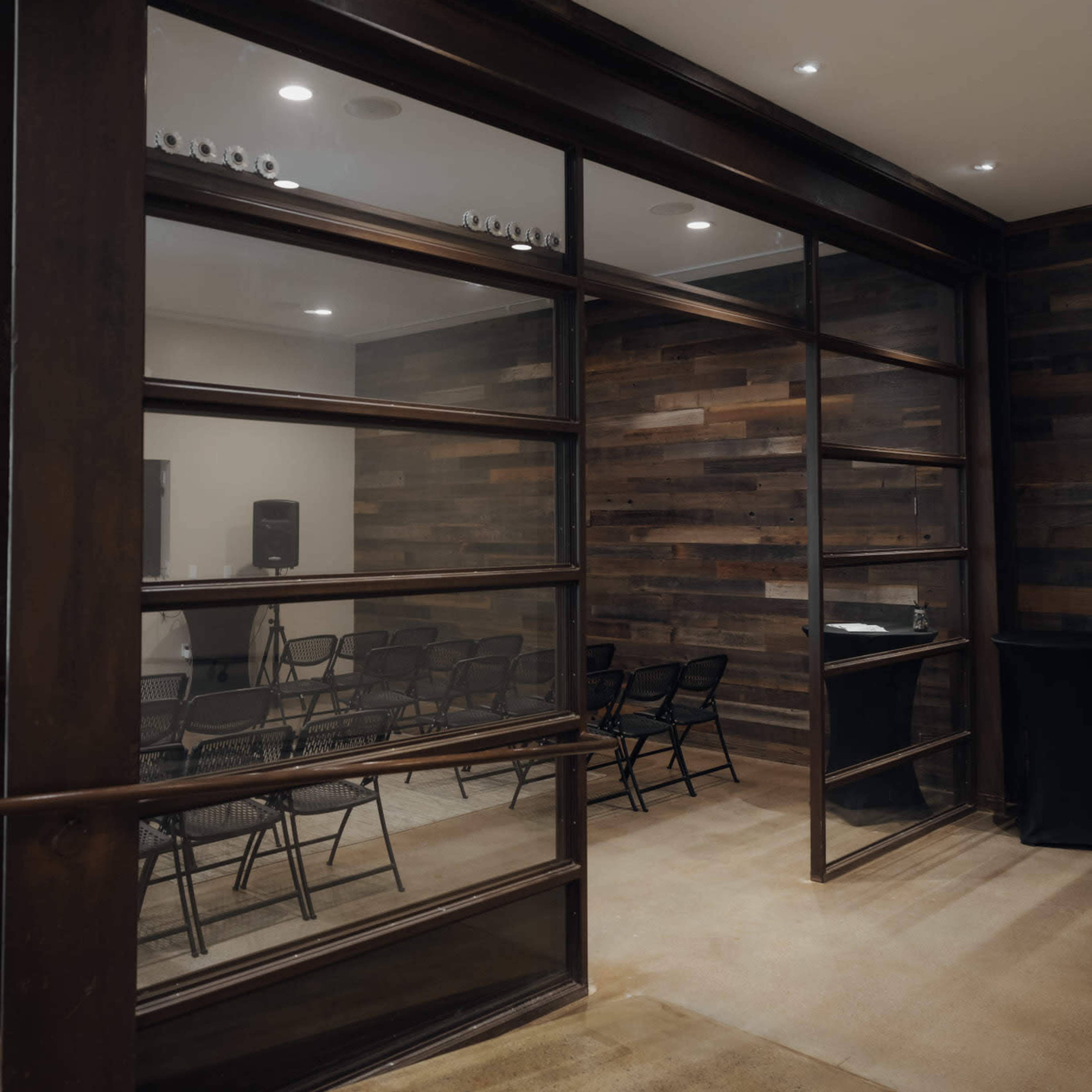 A room with glass walls containing several black chairs and a dark wooden interior.