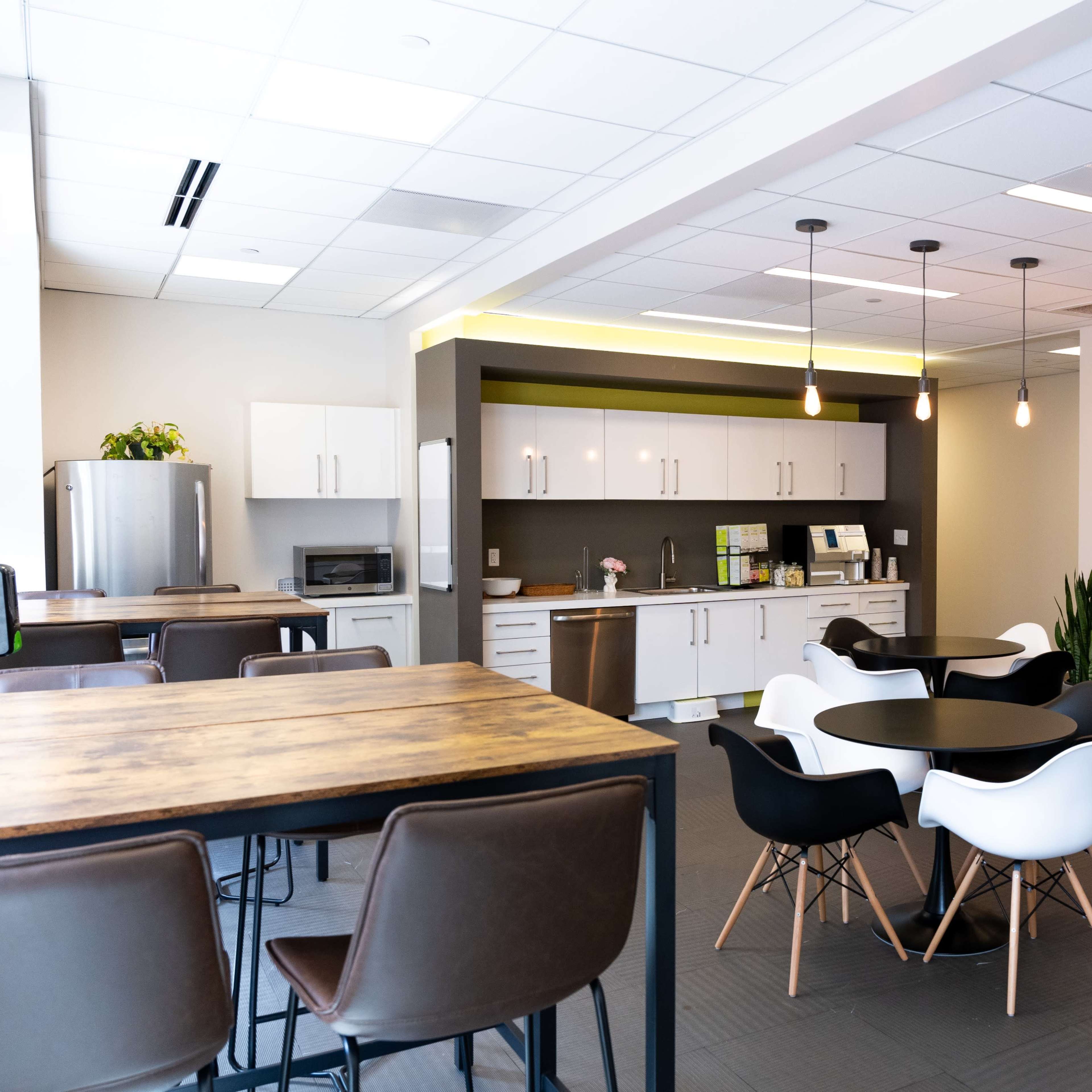 A modern kitchen and dining area featuring a table with chairs, a kitchenette with appliances, and pendant lighting.