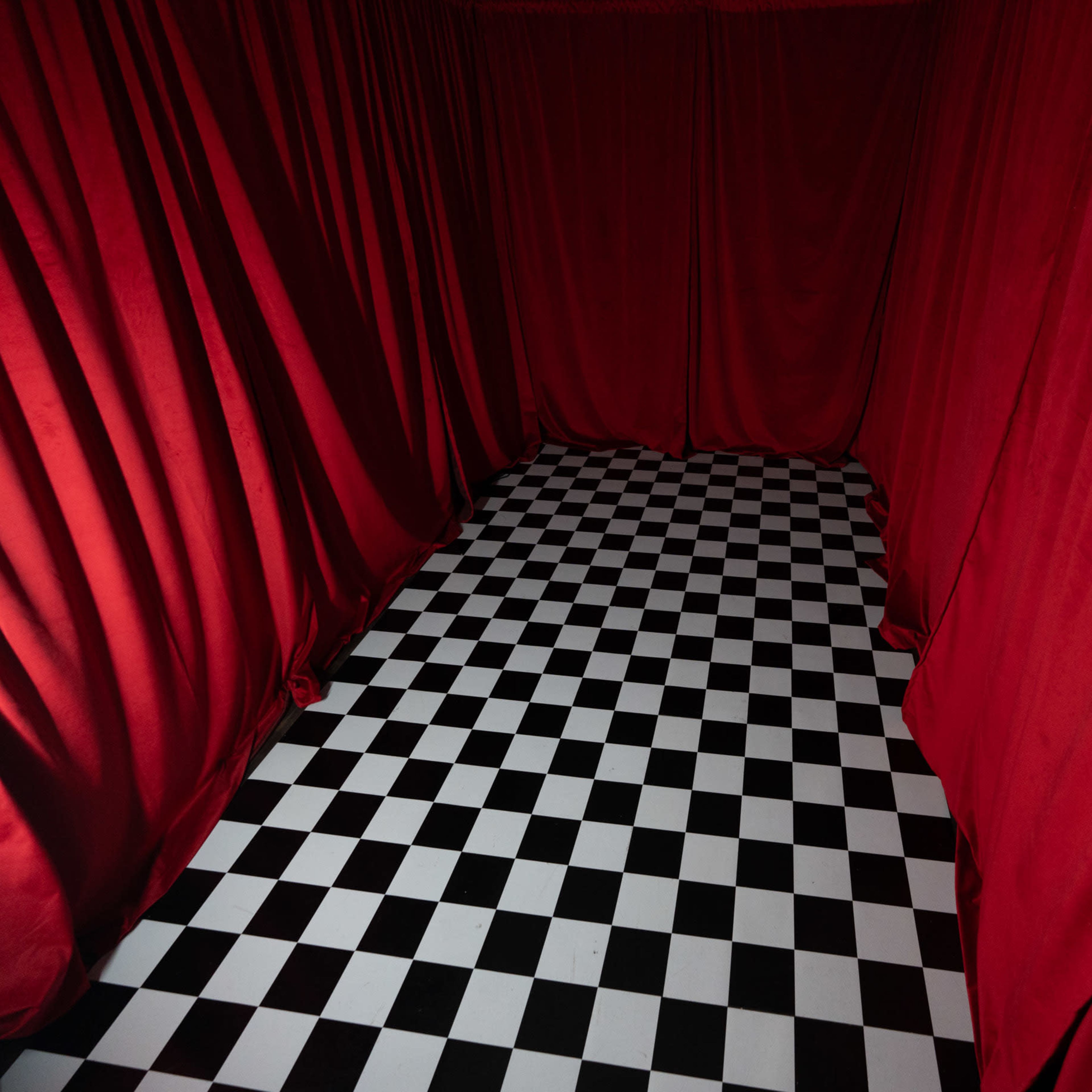 A small room with red curtains and a black-and-white checkered floor.