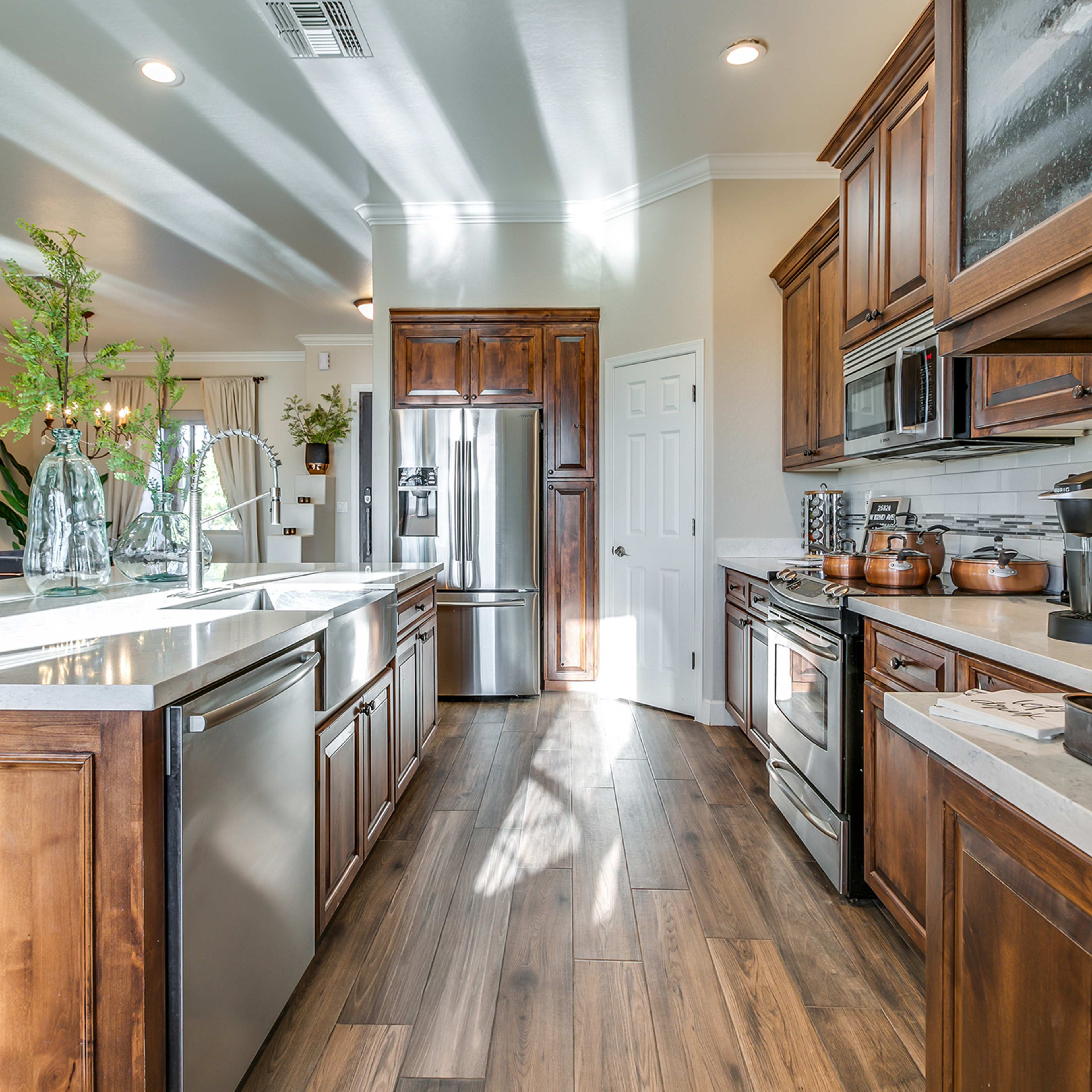 A modern kitchen with wooden cabinetry, stainless steel appliances, and a large island featuring a sink.