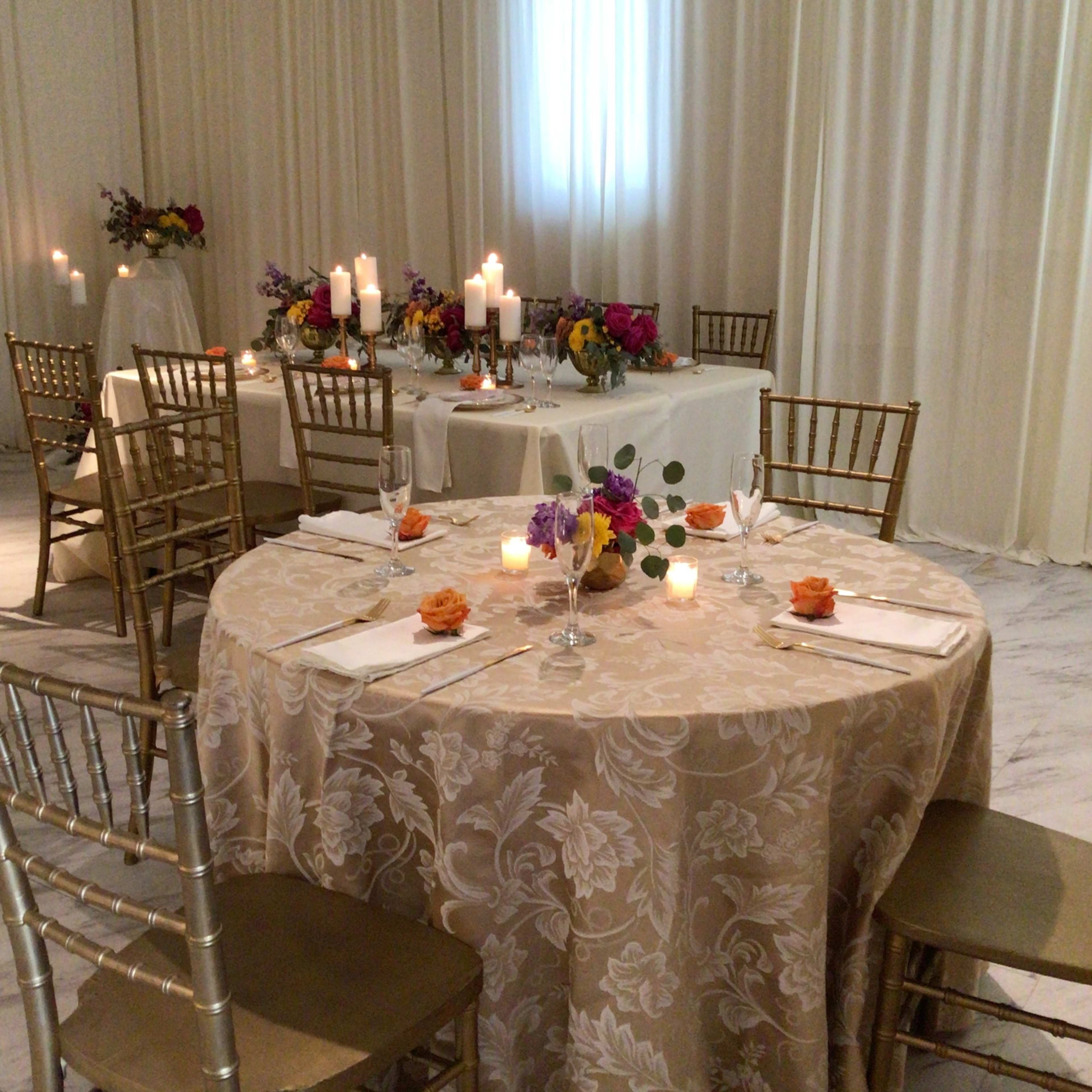 Elegantly set dining tables with floral centerpieces and candles in a softly lit room.