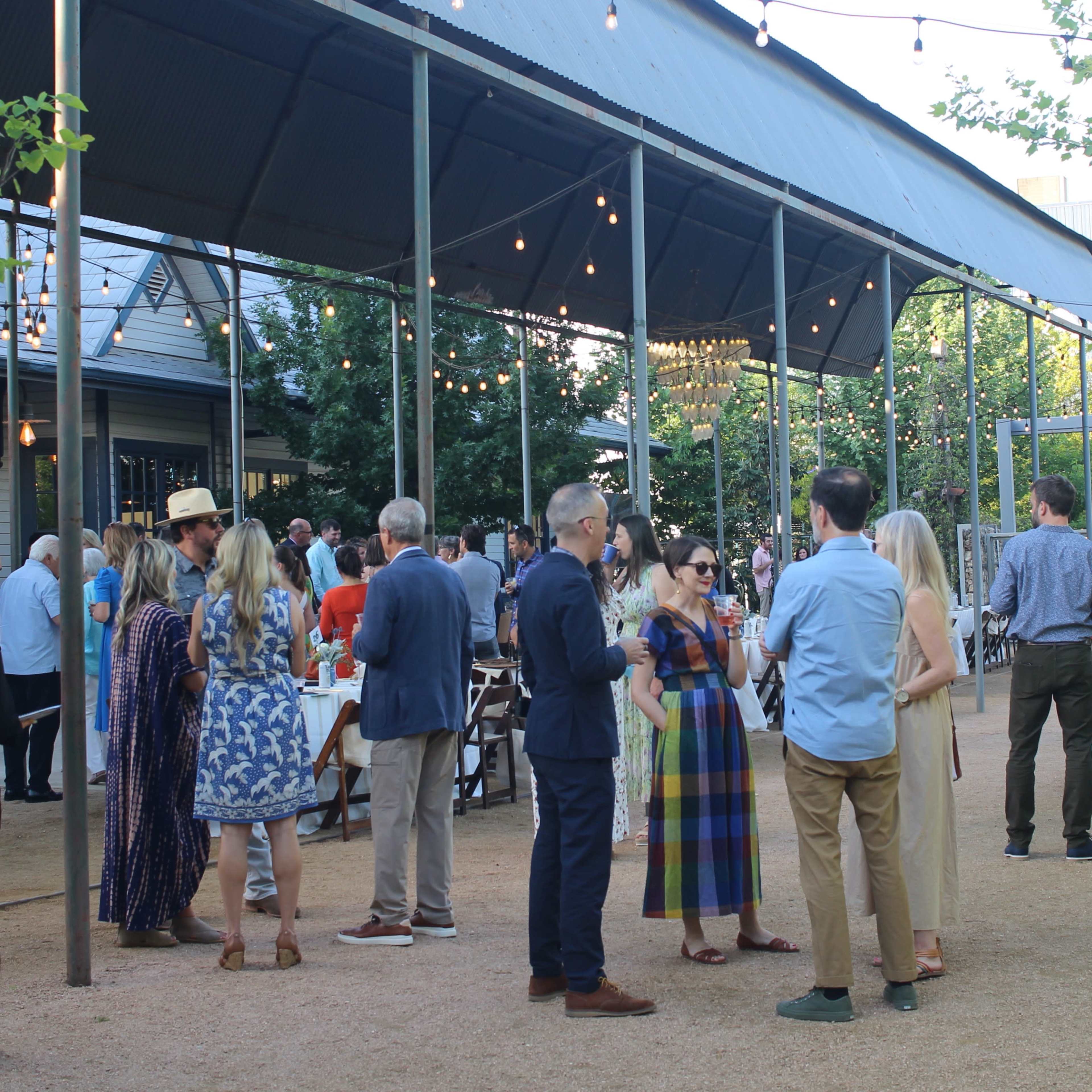 A large audience listens to a speaker at a panel event featuring a decorative stage with floral elements and branding.