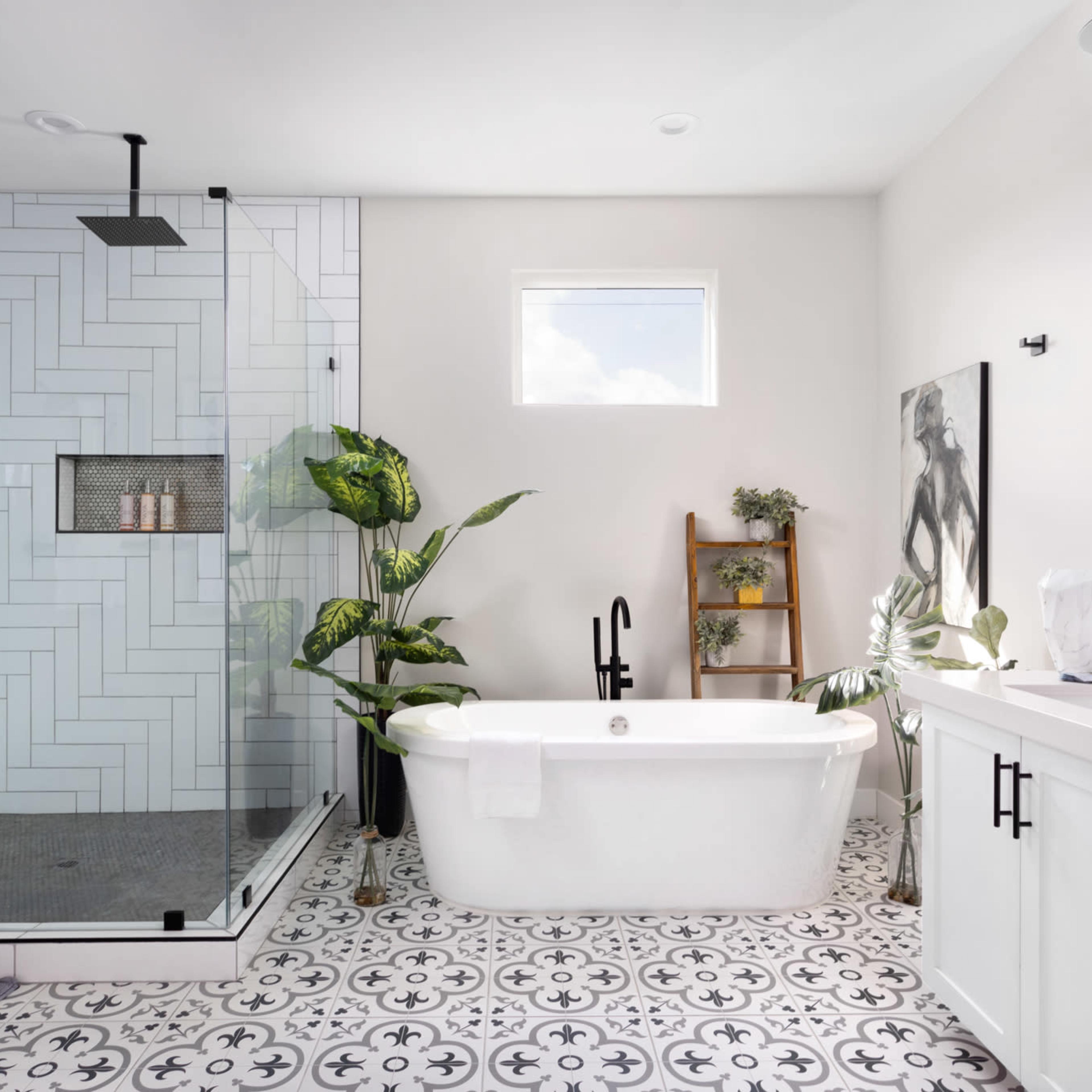 A modern bathroom featuring a glass shower, freestanding bathtub, and patterned tile flooring, with plants and a ladder shelf for decor.