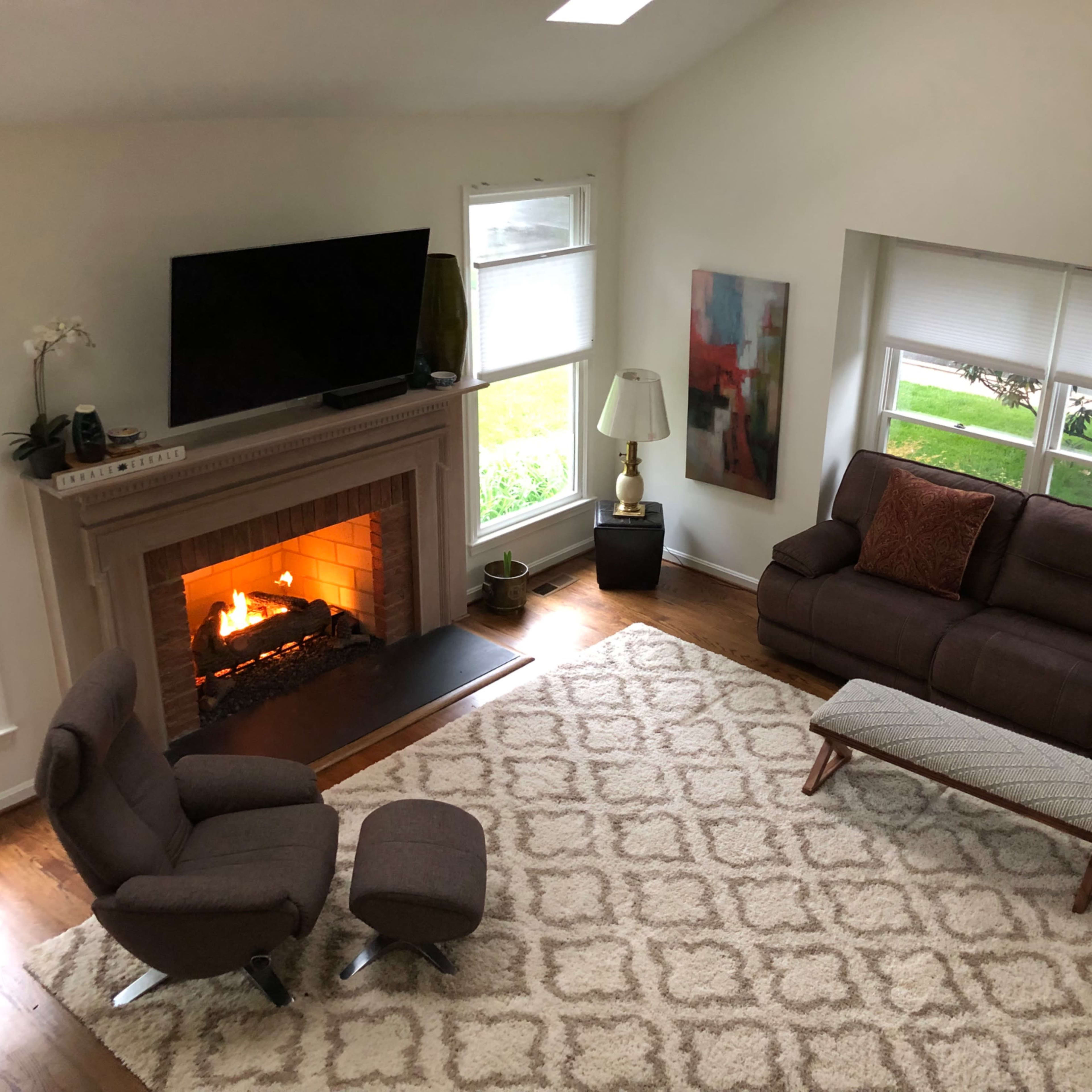 A living room with a fireplace, two sofas, a coffee table, and a television mounted on the wall.
