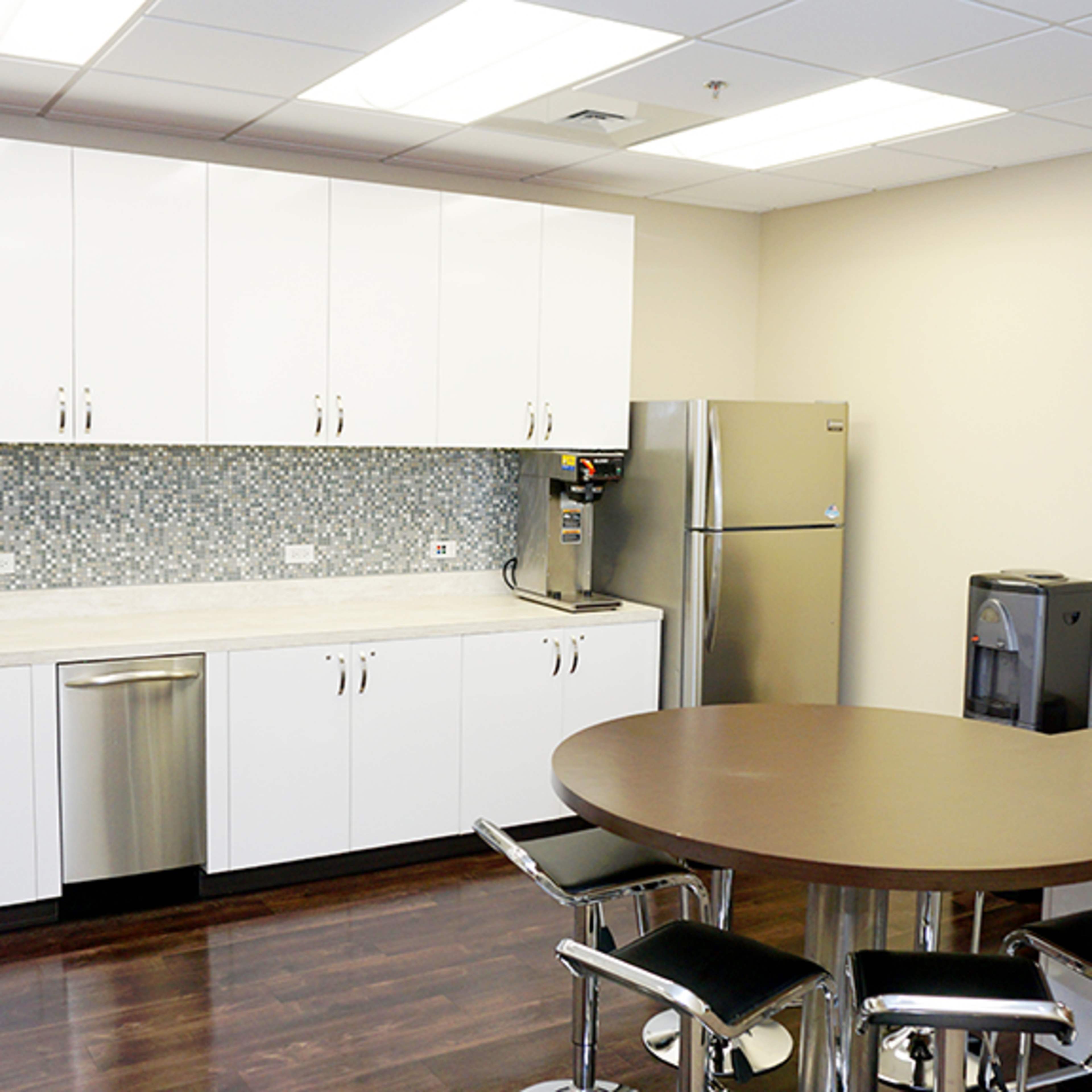 A modern kitchen with white cabinets, stainless steel appliances, and a dark wood countertop.