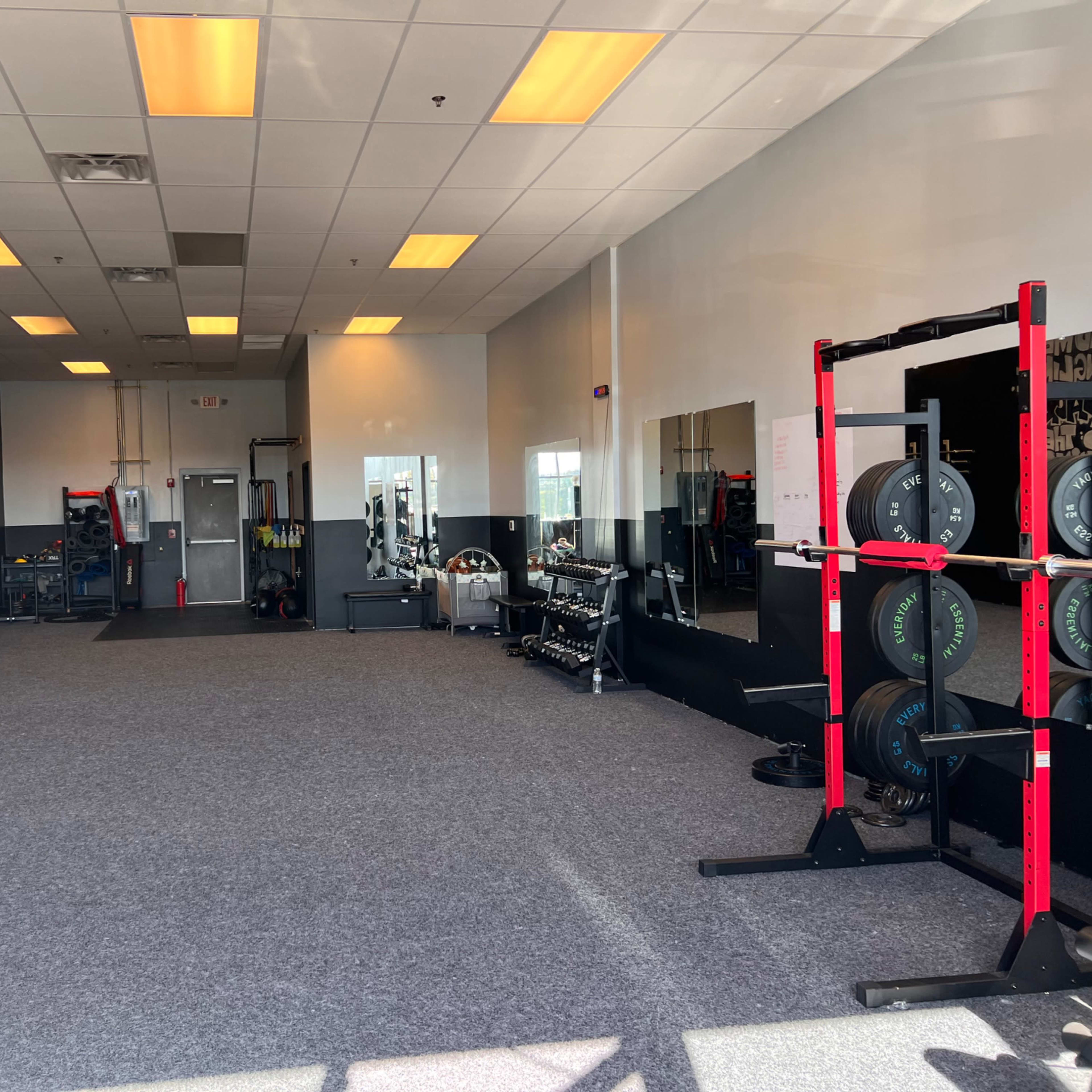 An empty gym with various exercise equipment and a mural on the wall.