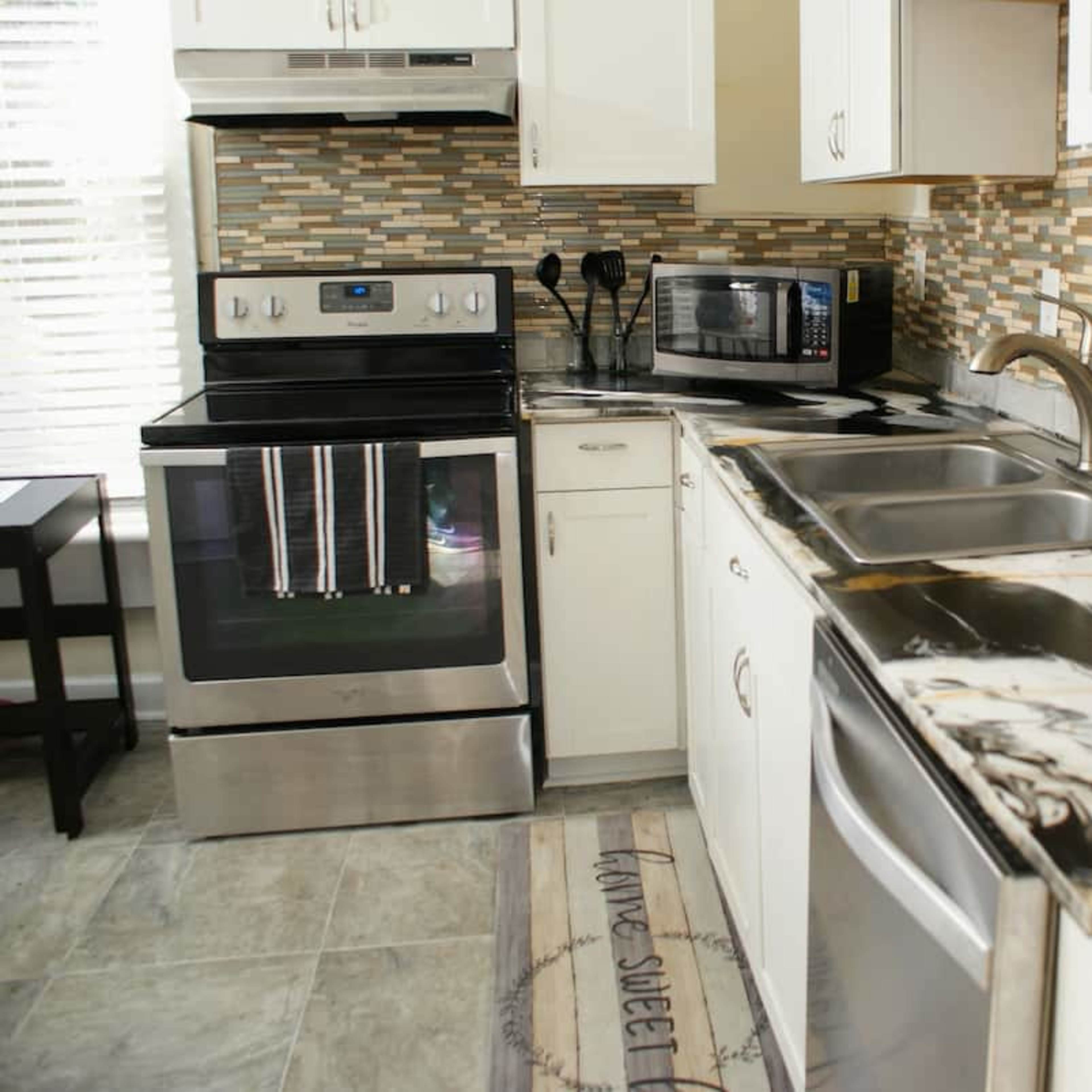 A modern kitchen with stainless steel appliances, a patterned backsplash, and a dual sink counter.
