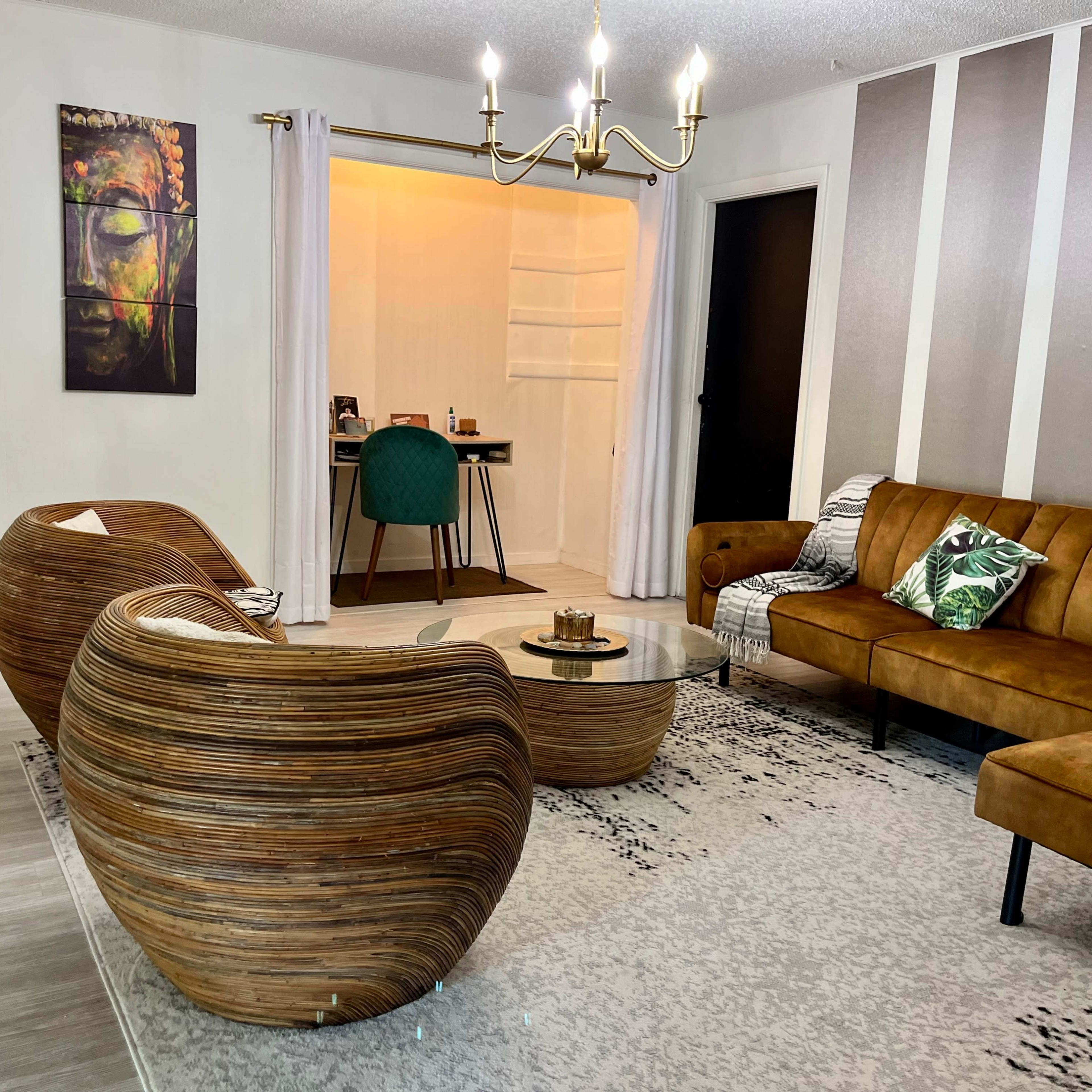 The living room features a wooden coffee table and two curved chairs, with a brown sofa and a desk in the background.