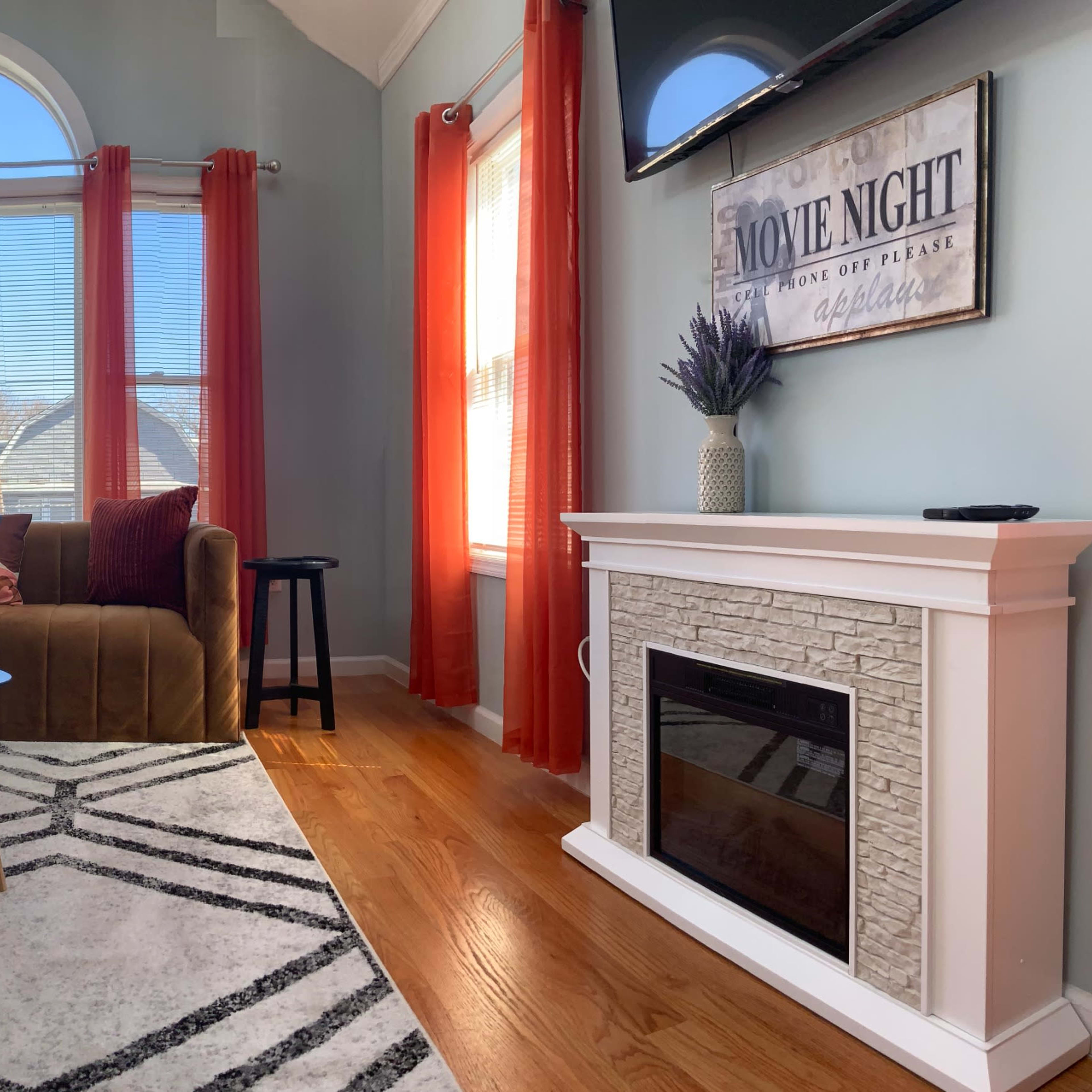 A spacious living room with a blue and brown seating arrangement, large windows, and a modern fireplace.